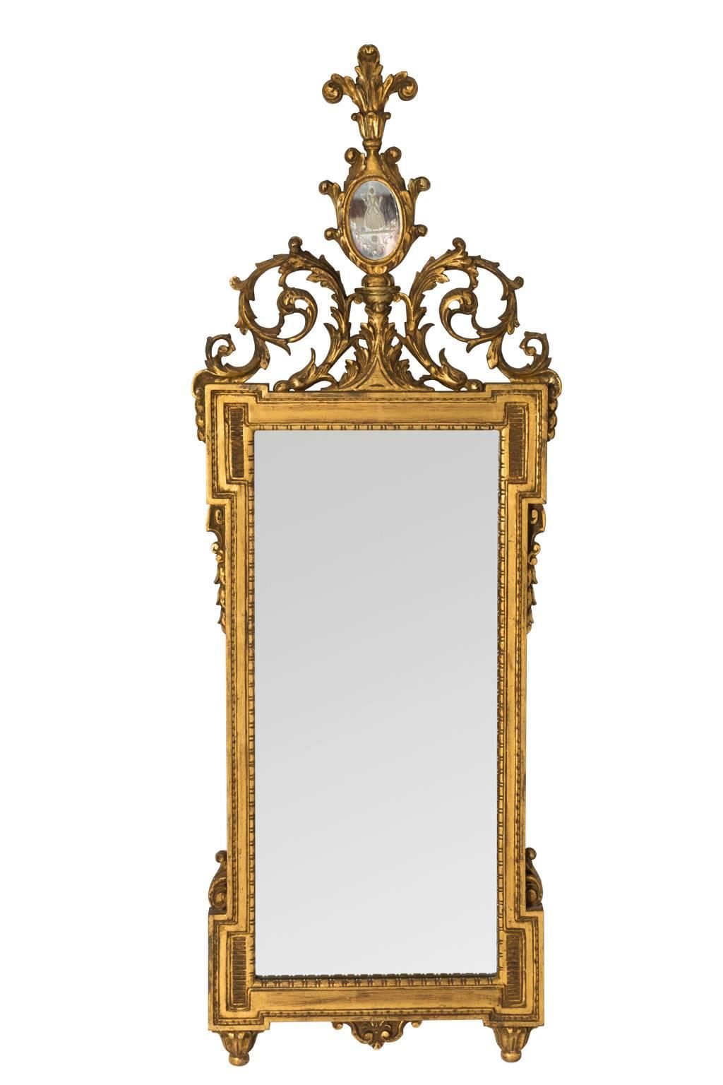 Pair of neoclassical gilded mirrors with dog ear corners, circa 19th century. The crown features scrolled foliage and an etched glass medallion.
 
