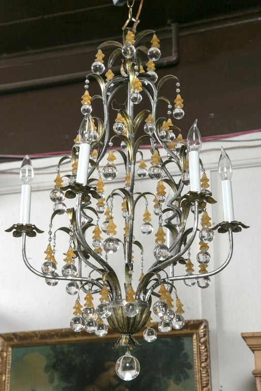 Small  double clusters of yellow-orange  glass  bell forms above the  round, clear glass hanging  drops. Lily form polished steel   frame. six  tubular arms topped with fanciful floral bobeche. Central  drop ball below.  In working order.