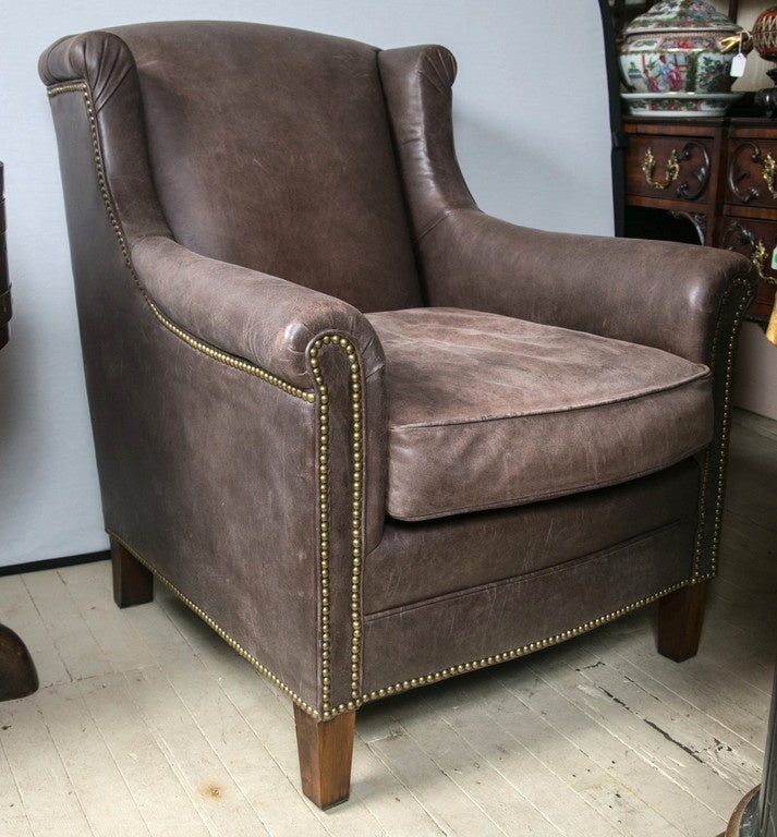 Extremely comfortable and of great quality, this pair have been barely used since purchased. There are short wings and a low arched back. Brass nailheads and short wooden feet complete the look. The leather is cocoa color and does show some minimum