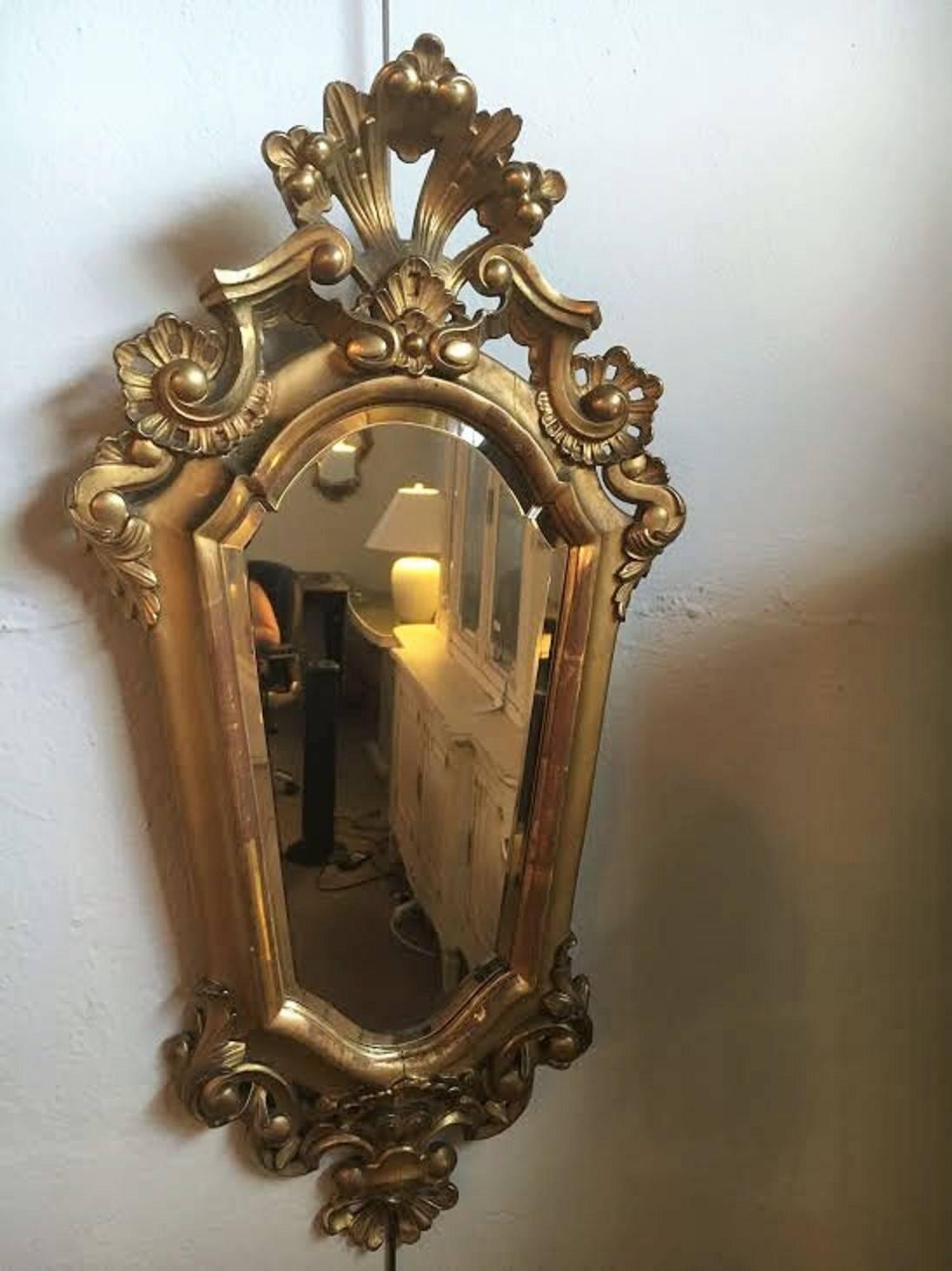 Pair of Italian gilt carved mirrors beveled glass conforming to frames. Open pediment, top and bottom. Each of these beveled finely frames mirror are small enough to place in any area of the home where decorative style is needed.