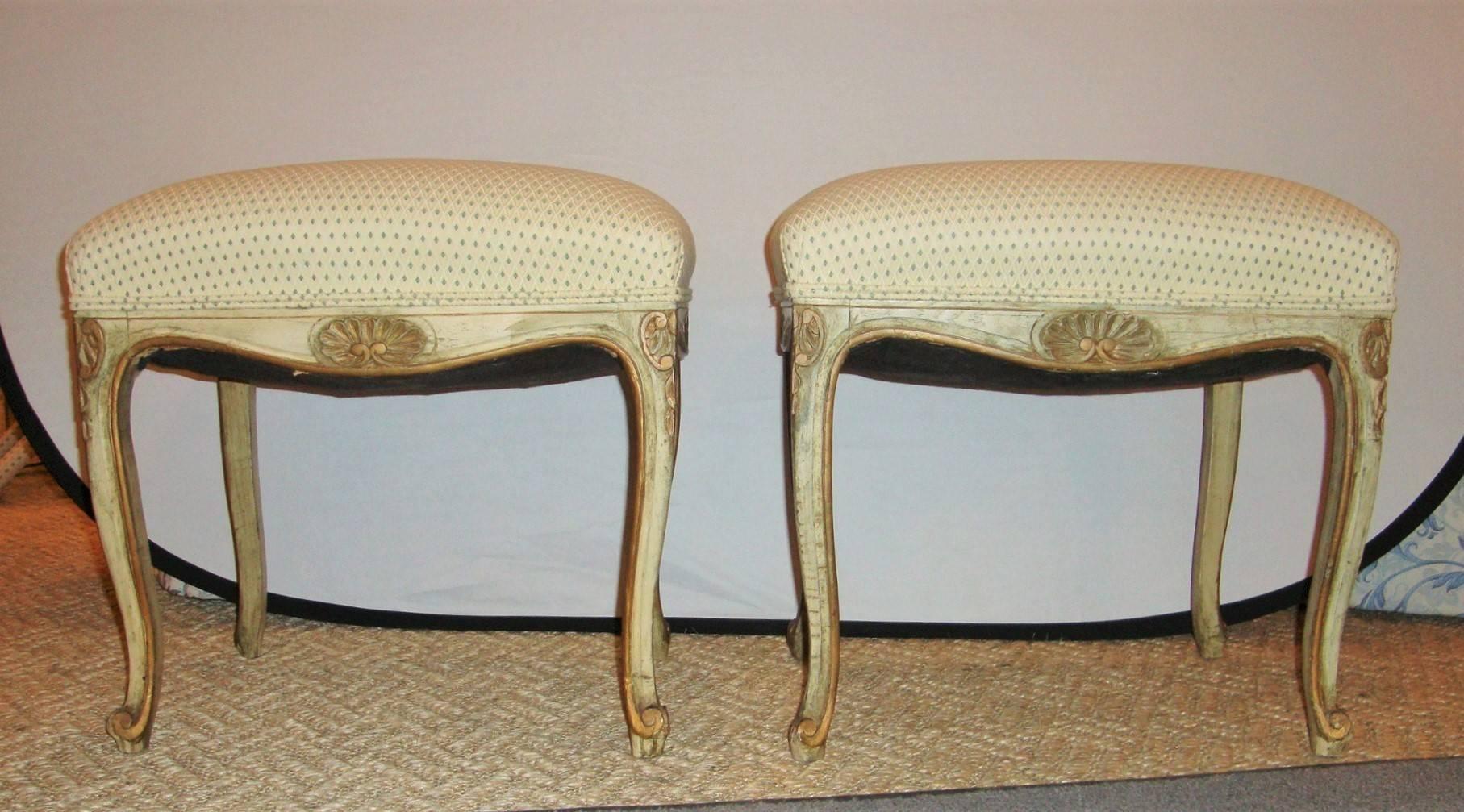 An elegant pair of French carved and painted stools, with gilt accents throughout.

 