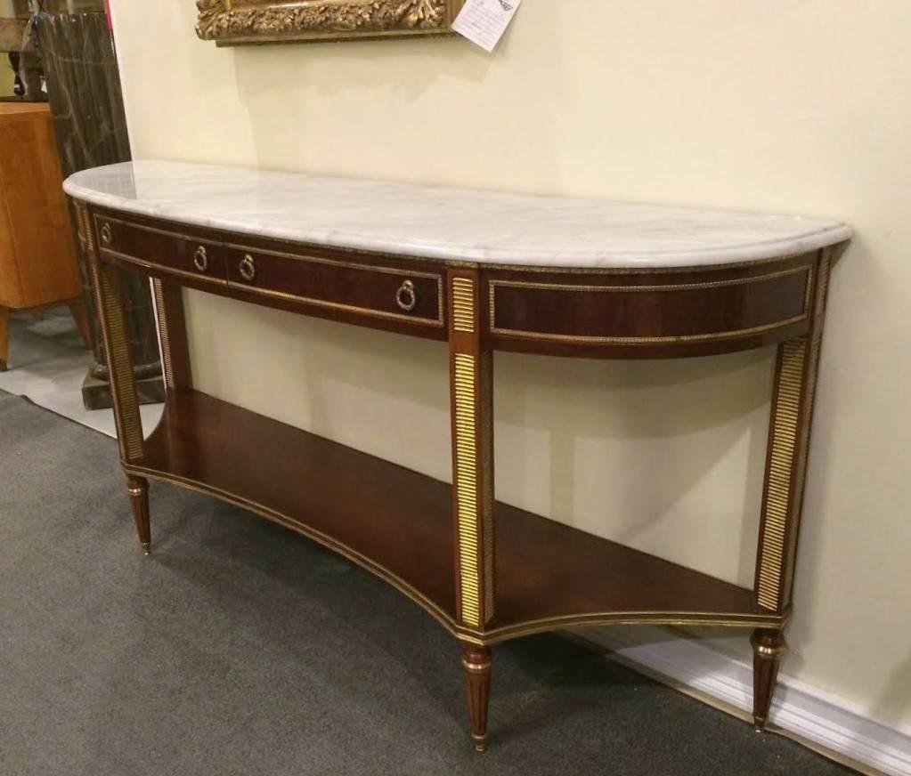 An elegant marble top demilune console table. Bronze mounted in the Maison Jansen style. The Louis XVI style with all-over bronze mounts in the Russian neoclassical fashion having double drawer fronts in demilune form with a lower shelf and