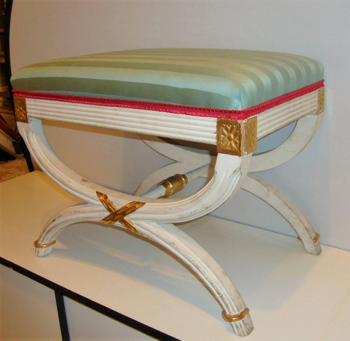 Hollywood Regency paint decorated “X” form bench or footstool. Off-white paint decorated and distressed with gilt gold hi-lights this fine decorative footstool is a prime example Hollywood Regency style.