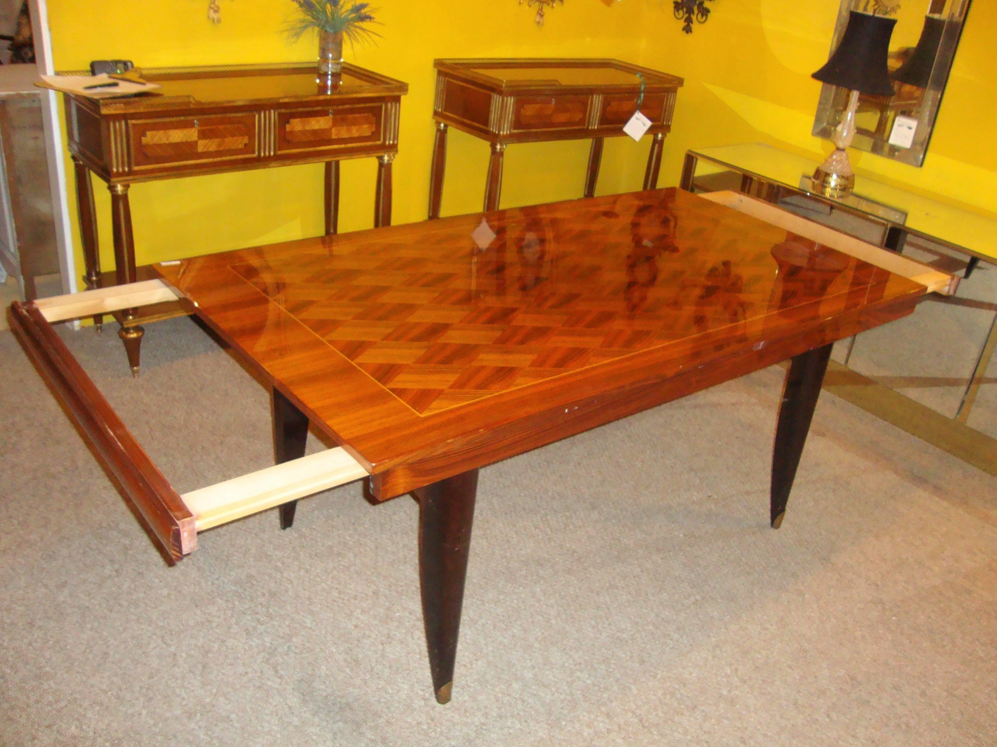 An Italian Mid-Century Modern parquetry inlaid dining table. This fine exotic wood dining table has four brass capped sprayed legs supporting the most decorative table top one could possibly fine. The table itself with two pullout extensions for
