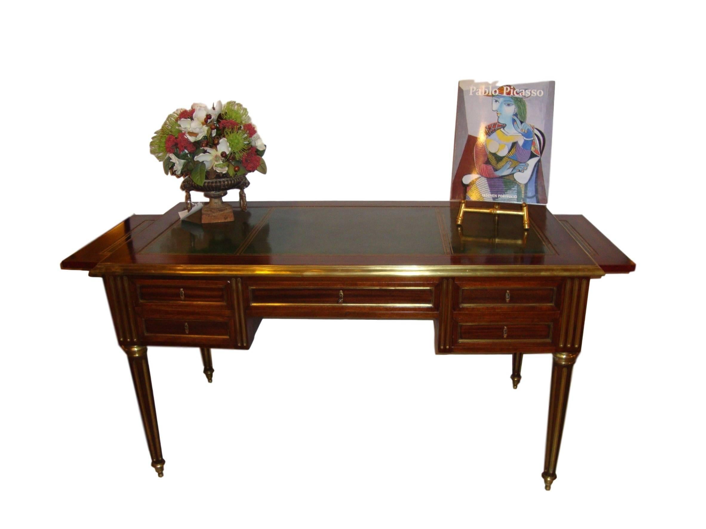 French Louis XVI style bureauplat finely bronze mounted. This fine custom quality bronze-mounted desk is fashioned in the Maison Jansen style. The center drawer flanked by a pair of smaller drawers all bronze framed. The sides also bronze framed