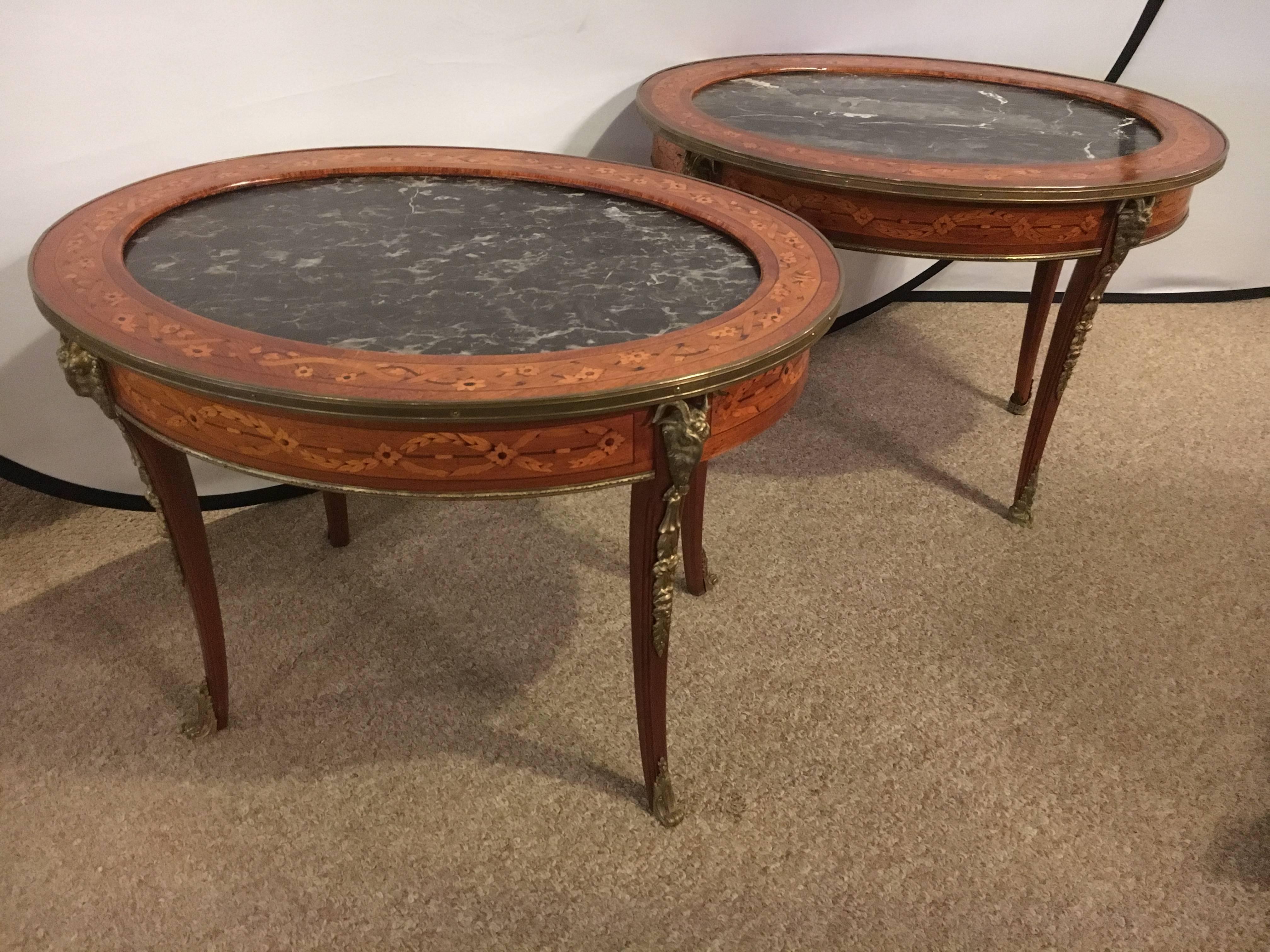 Marble-top bronze-mounted low/coffee table. The bronze claw feet leading to a curved leg terminating in a ram's head with flowing leaf design. The top, finely inlaid with a marble set into the center. The overall top with a bronze border. Inlaid