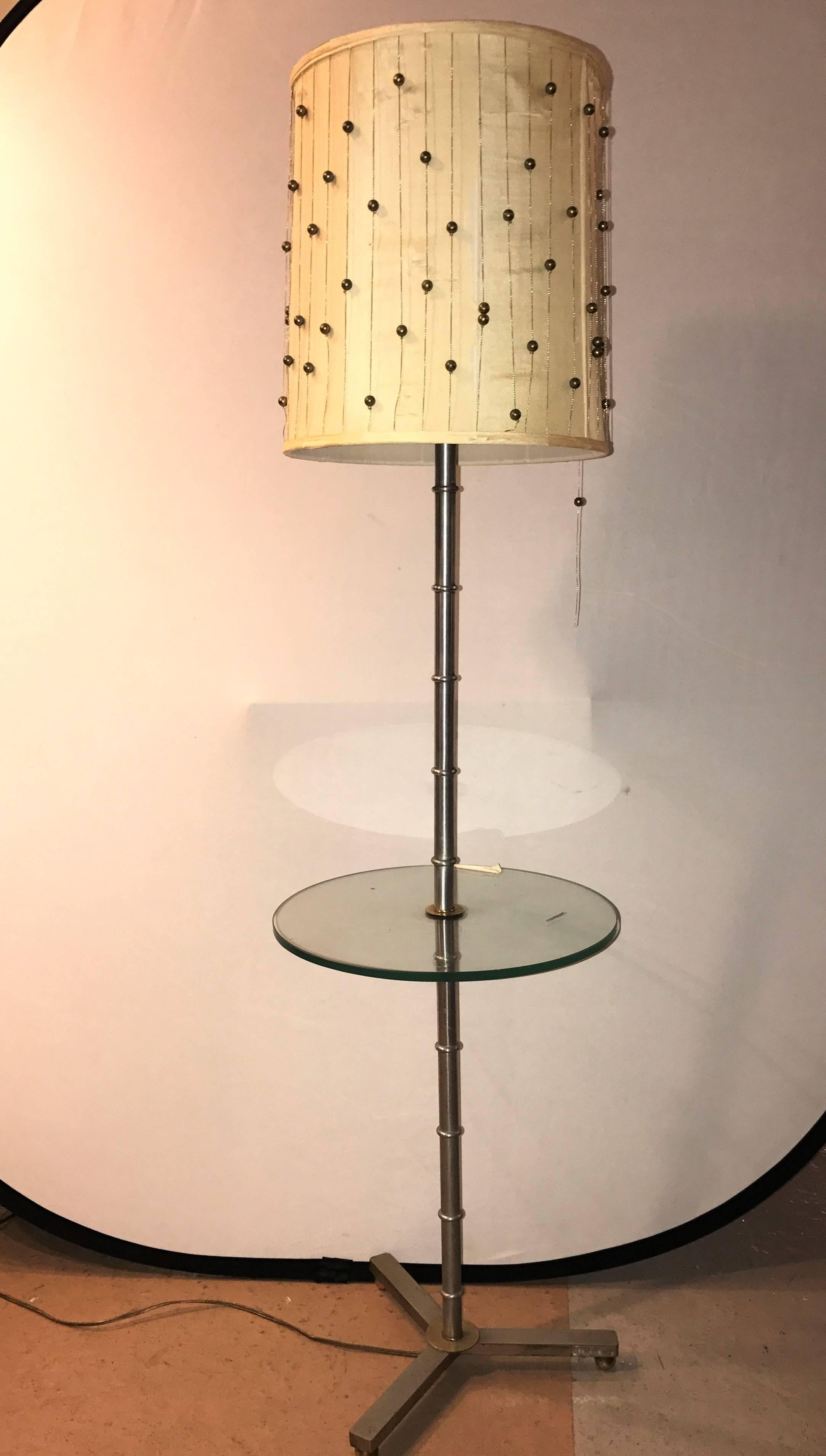 A faux bamboo form chrome standing floor lamp table Art Deco in form. The chrome Y shaped base on circular feet leading to a sleek chrome bamboo form center column which supports a circular glass tabletop. The whole taking two sixty watt standard