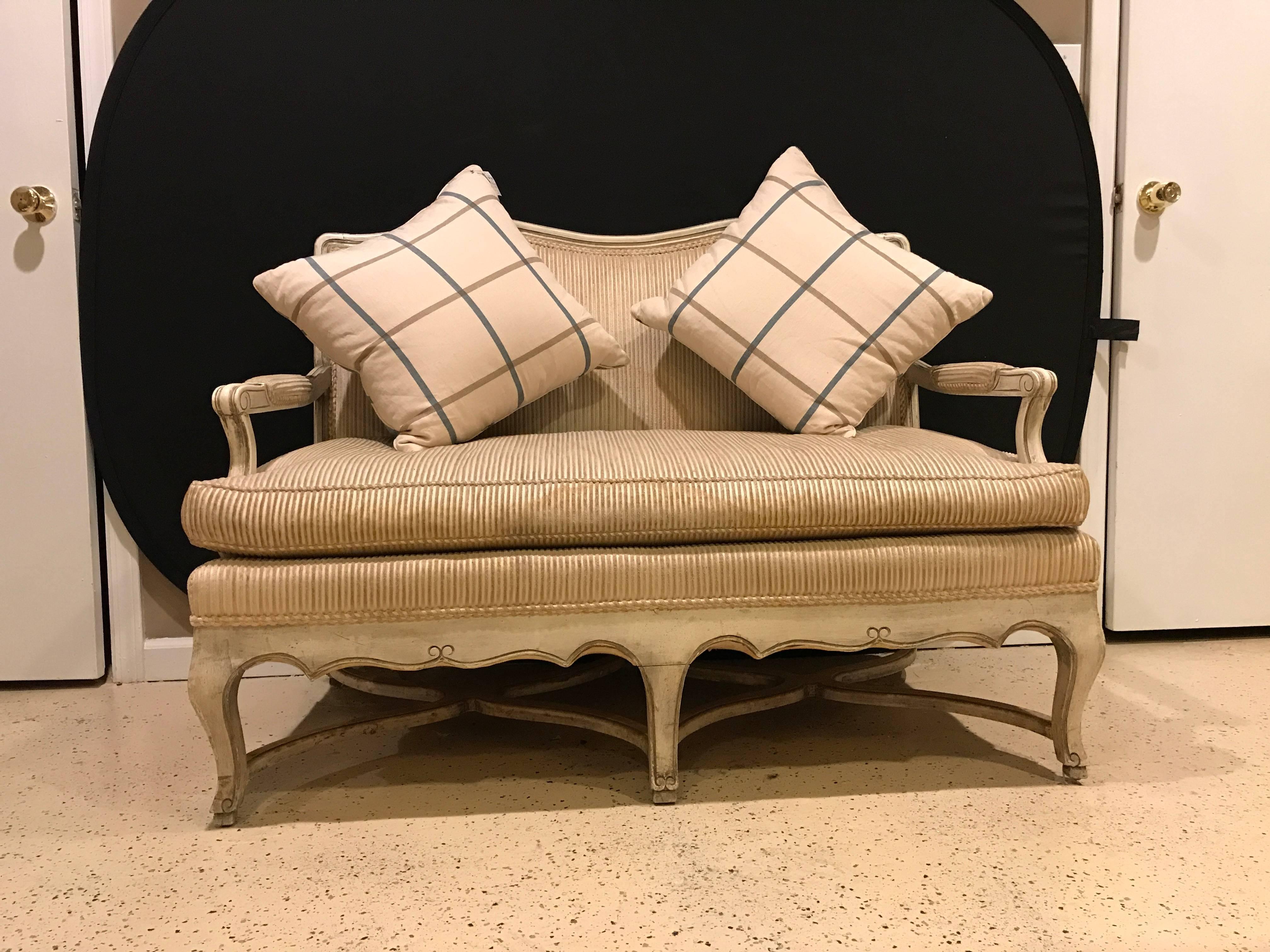 French paint decorated settee in the Swedish fashion. This Louis XV style settee or loveseat has a nice gilt and paint decorated frame with painted matching arms and a cushion seat. The upholstery can use a good cleaning or possibly be changed and
