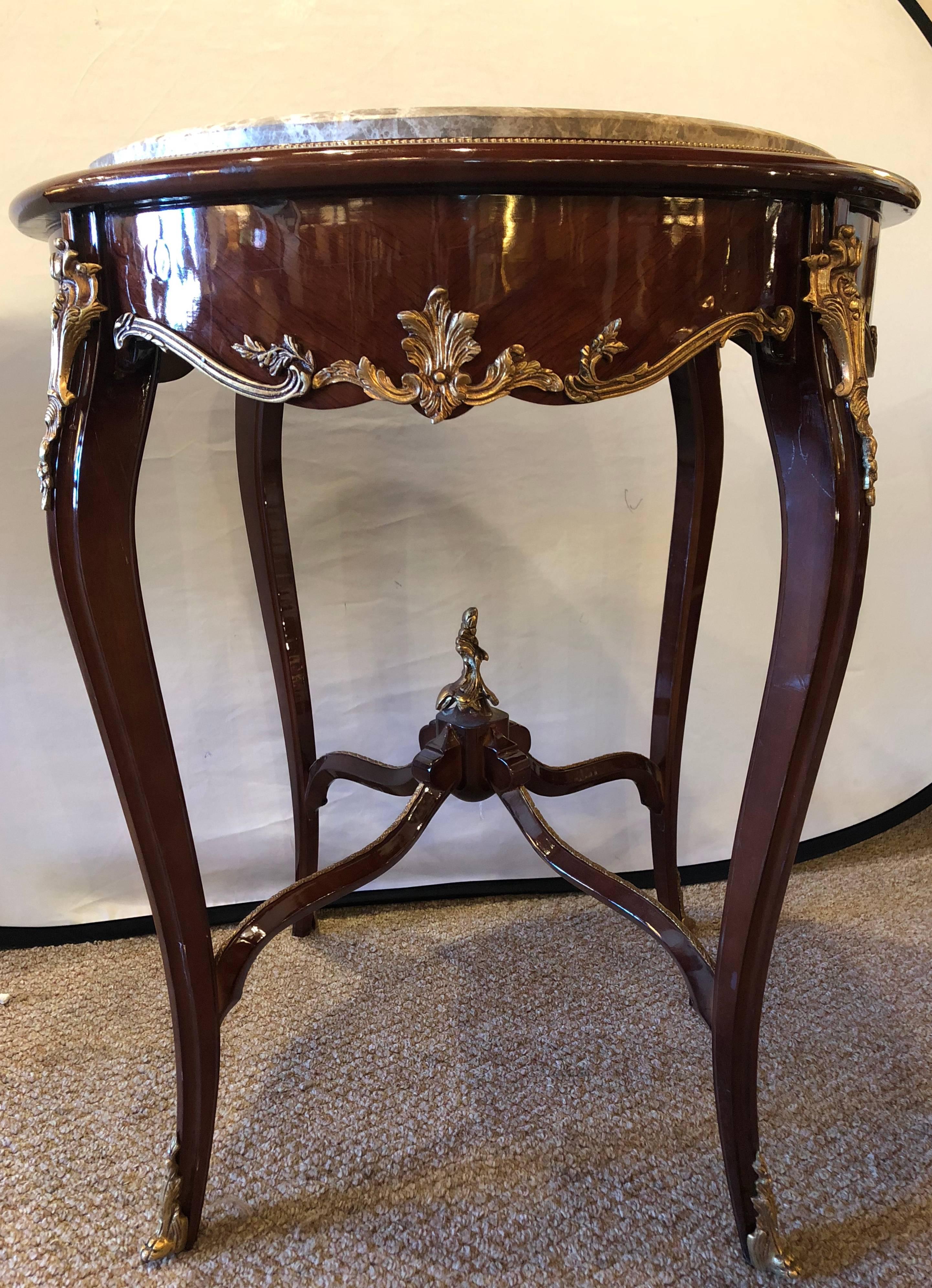 Pair of Louis XV style bronze mounted highly detailed marble top end tables. Each having a marble top sitting on a curved and carved base with bronze mounts.