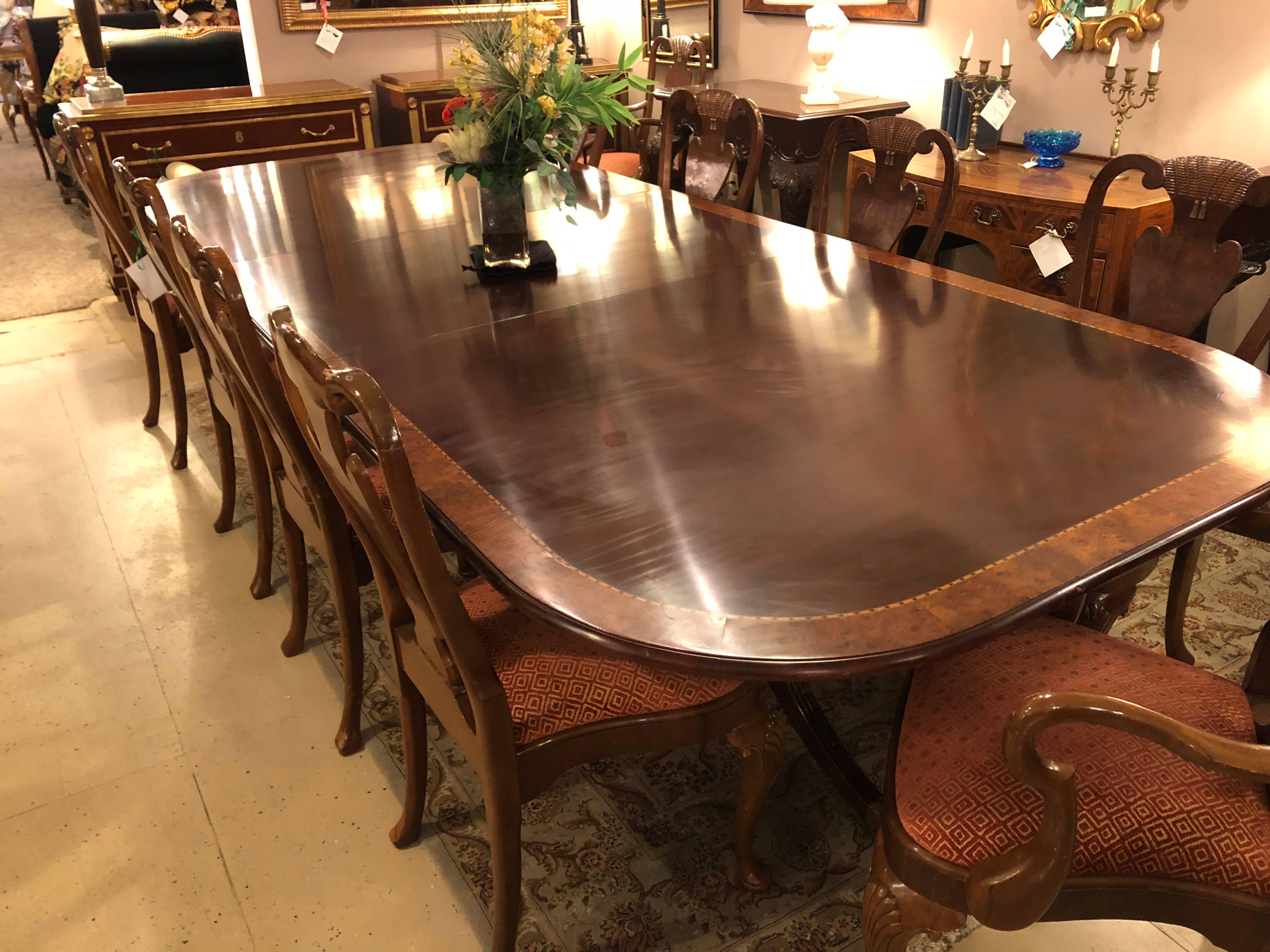 Monumental Georgian style banded dining room table with two 30 inch leaves. Table Width measures 156 inches with fully extended. Finely carved tripod double pedestal legs on brass casters support this burl-wood banded top dining table. The banding
