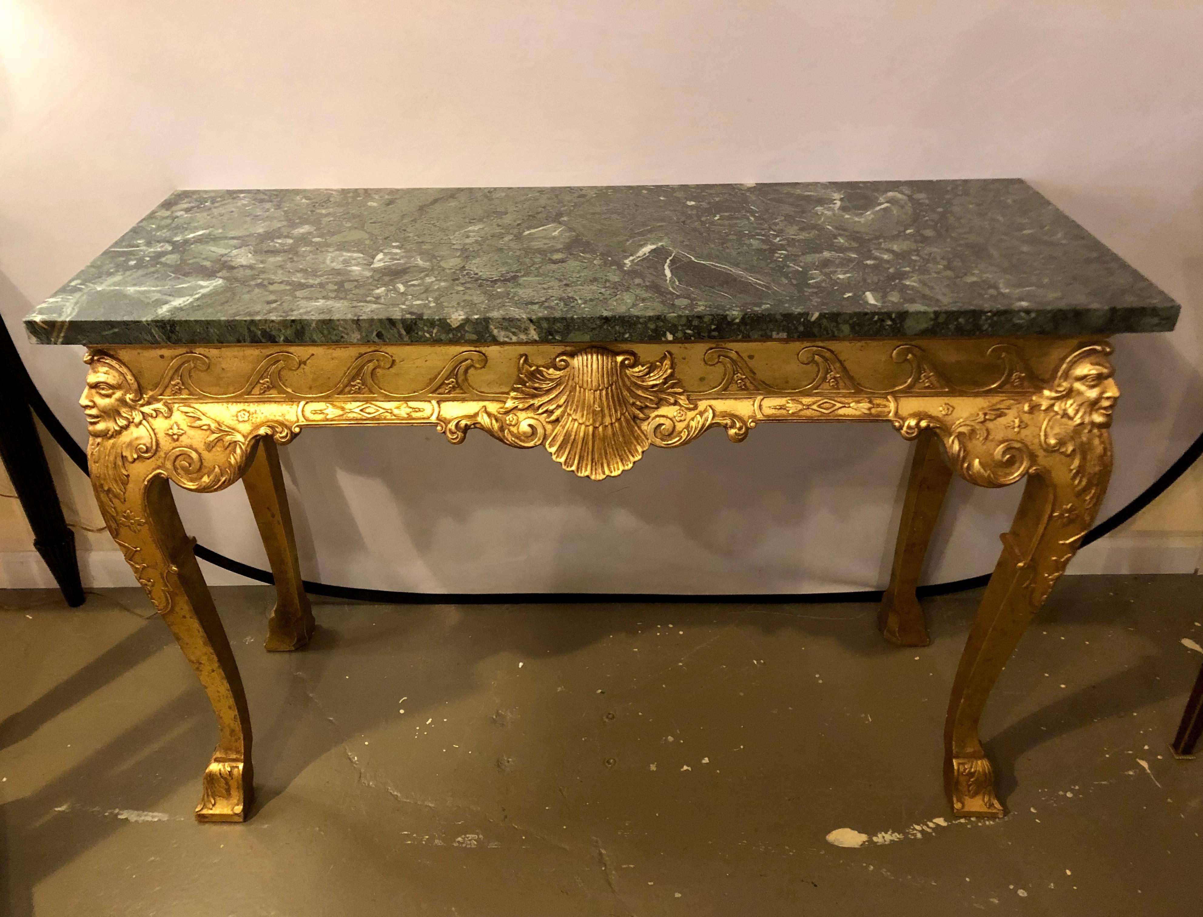 Pair of George II style carved giltwood and marble console tables, late 19th century. Olive green and white-veined marble top. Vitruvian scroll and shell-carved skirt, cabriole legs with masque heads on sides and front supported by Marlborough feet.