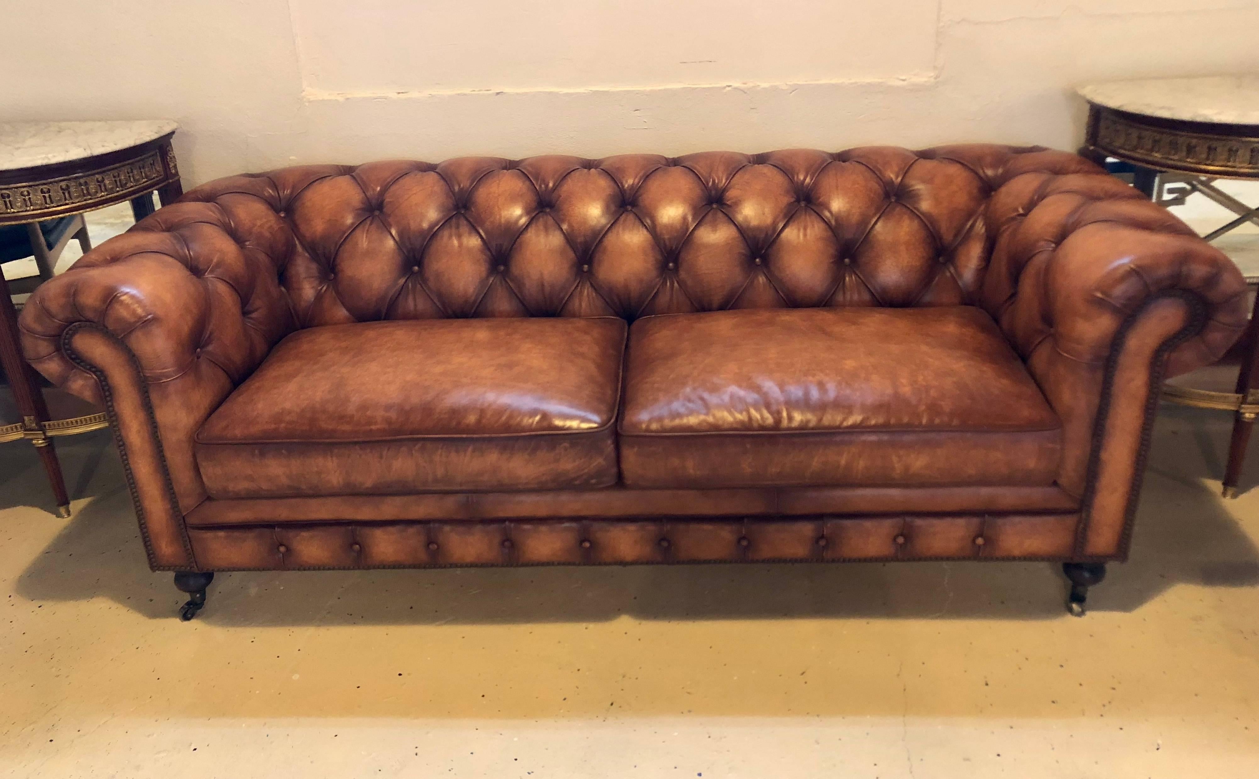 An English worn leather Chesterfield sofa. Supported by bun feet on brass casters stands this very comfortable sofa in a fine worn leather.