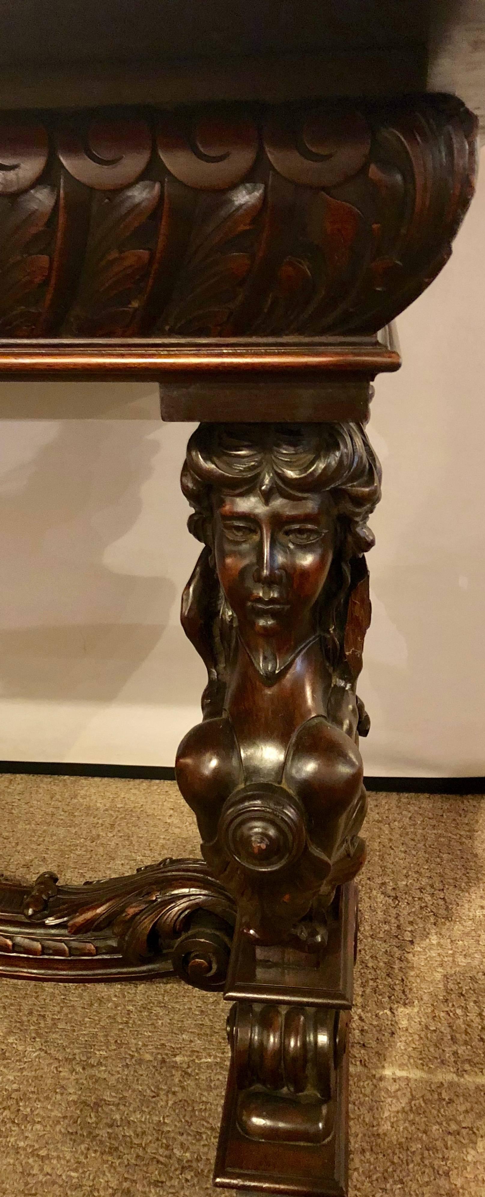 This figural carved Herter or Horner Brothers style library table or desk with winged maidens is truly spectacular. The tabletop made of solid wood supported by a group of four bare breasted winged full bodied maidens flanking a centre column. The