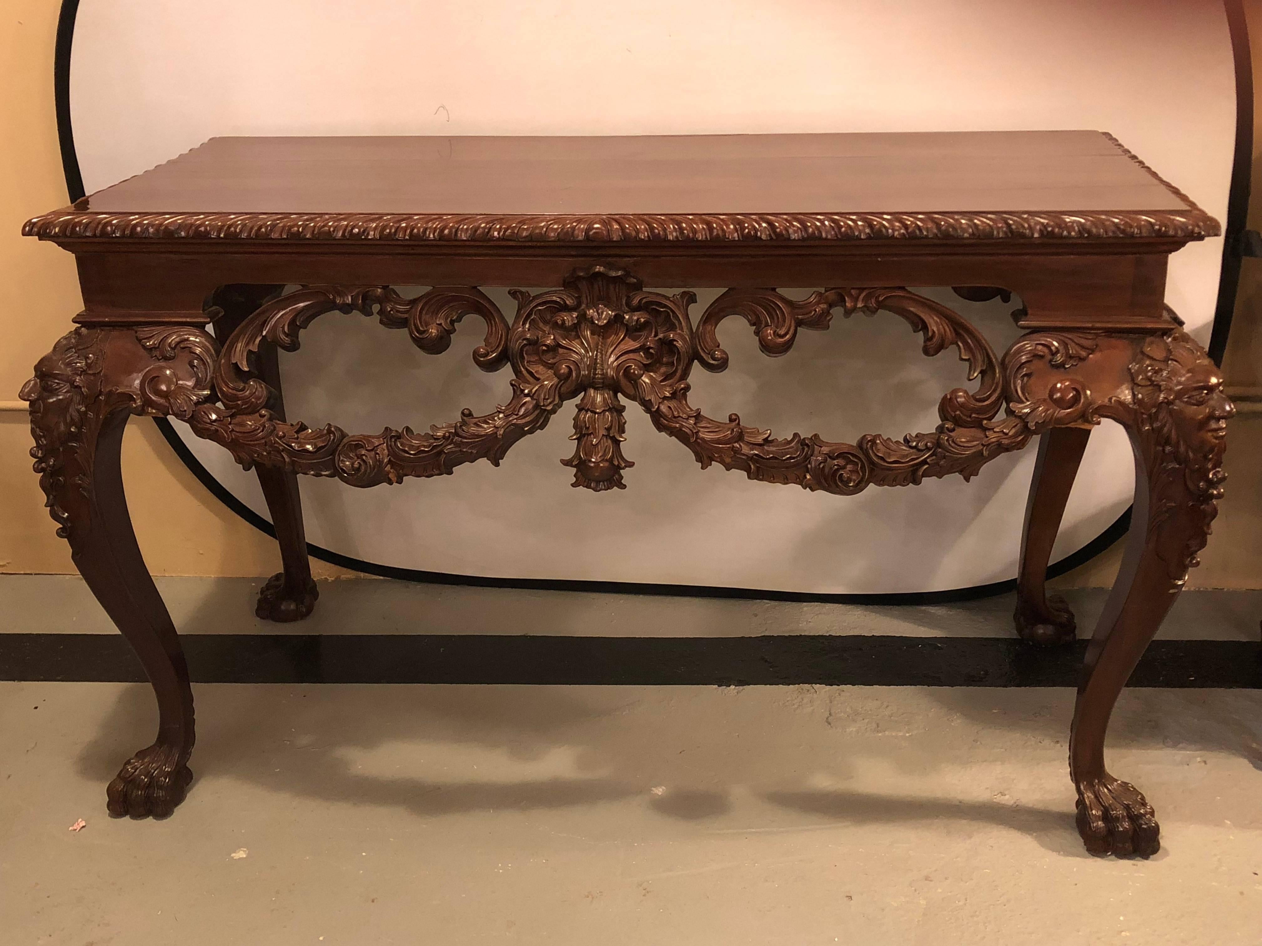 A custom carved console table with claw feet and carved heads, circa 1940s. This finely carved and detailed console or sofa table has Horner brothers quality wood work.
