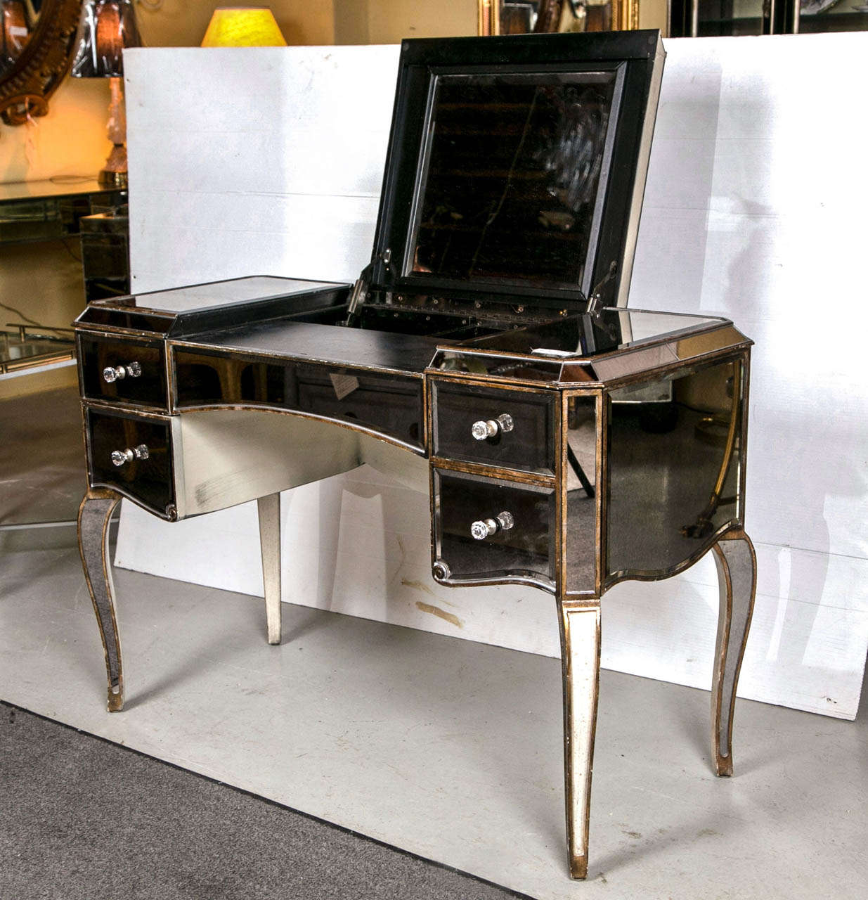 A fine mirrored curved gilt legged five draw vanity accentuated with crystal knobs. The sweeping mirrored legs finely framed in a wooden gilt gold design. The centre flip-top drawer having hide away interior compartment, flanked by a group of four