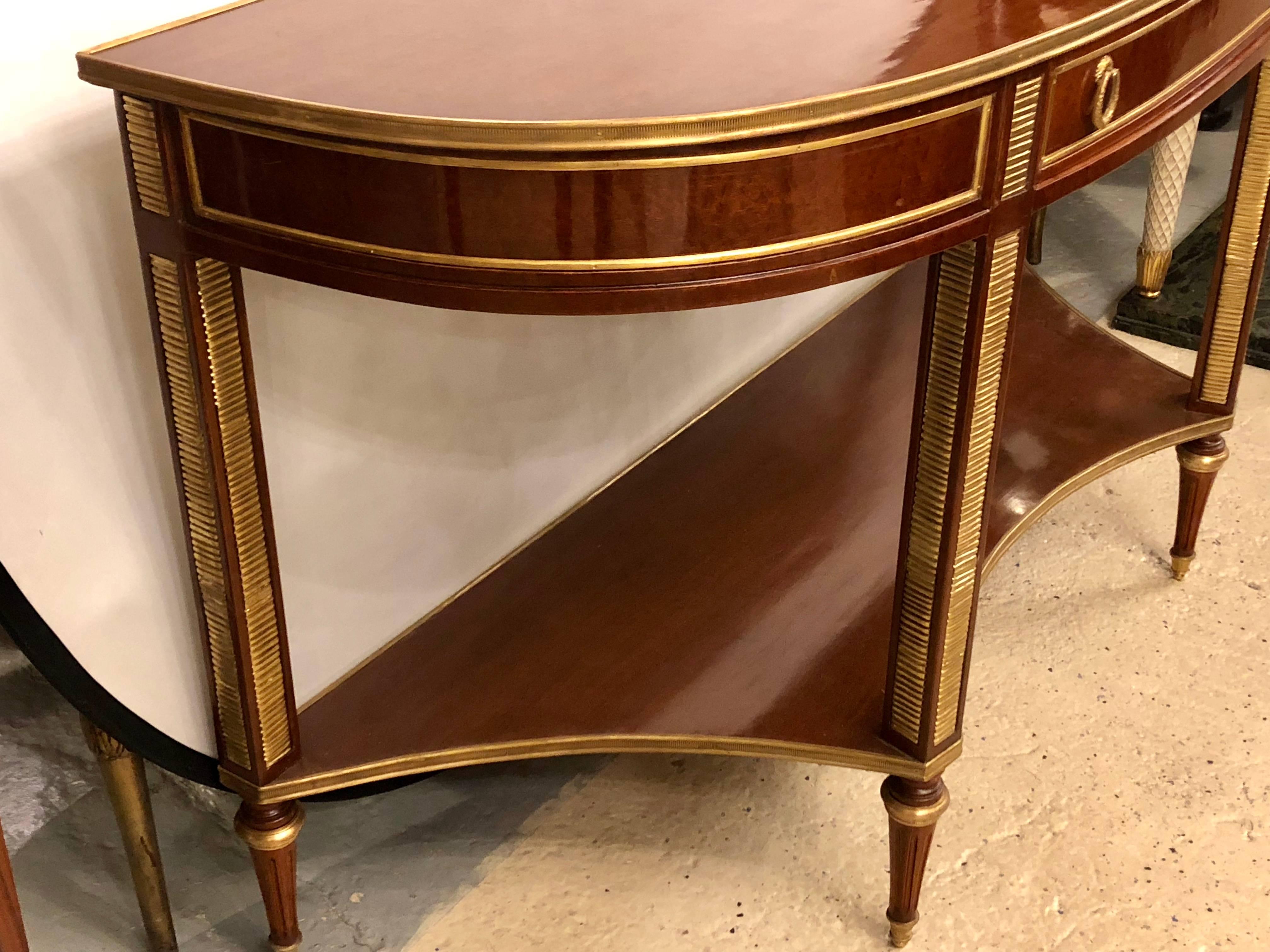 Pair of demilune mahogany bronze-mounted Russian neoclassical consoles with inverted lower shelves. This fine custom quality Louis XVI pair of consoles sit on bronze-mounted tapering legs leading to a inverted bronze framed shelf. The upper case has