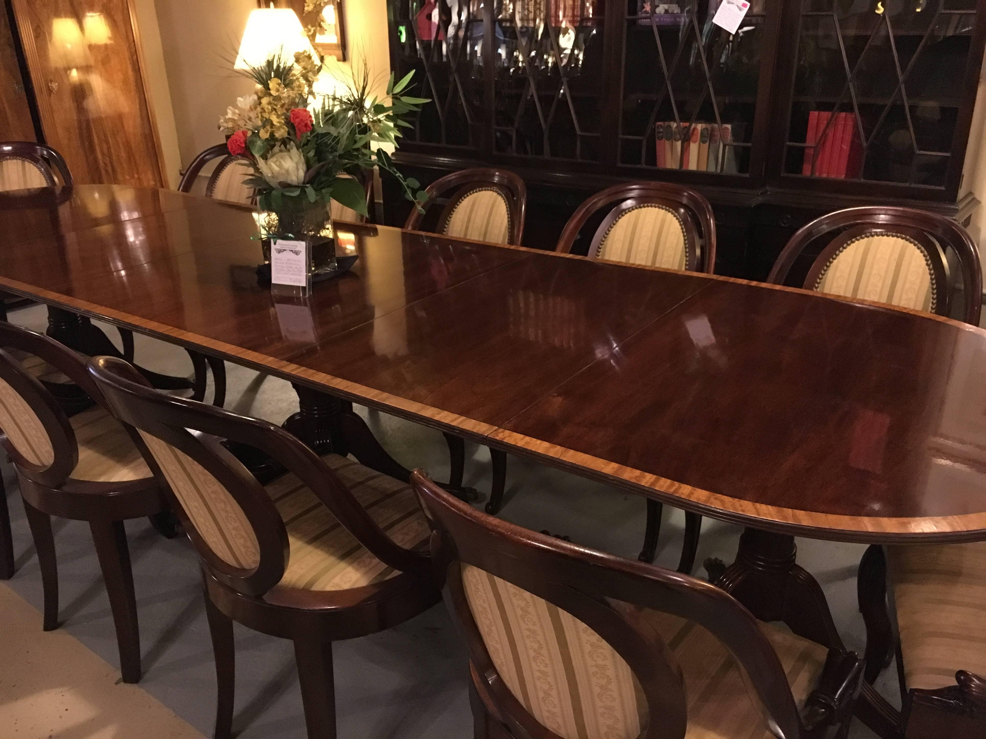 A banded mahogany Georgian style triple pedestal dining table. A fine custom quality dining table that has recently been polished having two (20 inch) leaves. This triple pedestal dining table sits on bronze claw feet with casters. The bases with