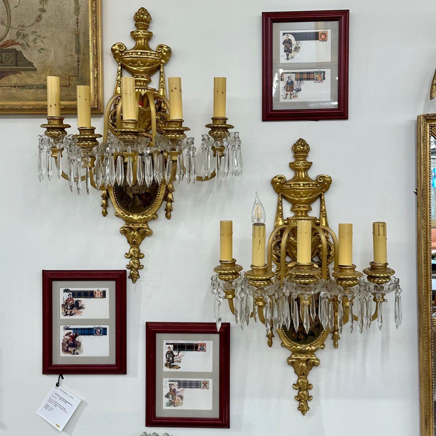 Pair of French Louis XVI Style Bronze and Crystal Rams Head Five Light Sconces
 
Pair of bronze and crystal ram's head and floral plaque decorated sconces. Each Louis XVI Style sconce with ribbon and tassel having a hand painted floral oval scene