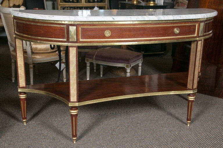 Pair of palatial Russian neoclassical style demilune consoles by Maison Jansen. This is simply the finest workmanship by this iconic designer. The sharp tapering legs with bronze sabots and terminating in bronze circular cups support a lower bronze