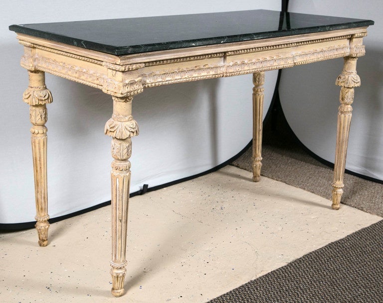 Louis XVI marble-top console table. Custom quality distress console table displaying a forest green marble top with white veins throughout. The sturdy tapering legs have carved detail that adds character to this piece support a carved distressed