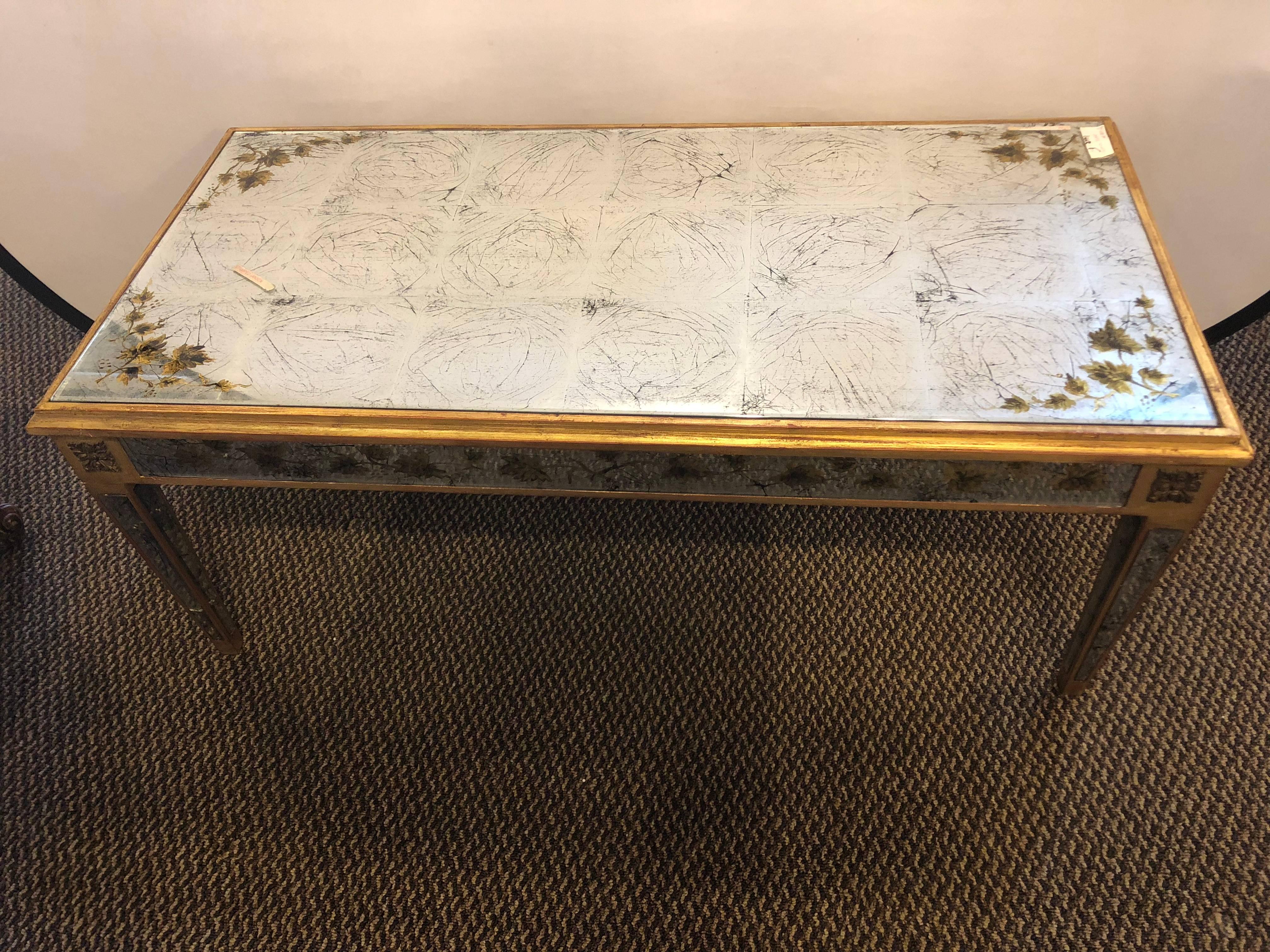 A fabulous Venetian style all-over églomisé glass coffee table with gold-leaf foliate pattern and carved bronze medallions. Stamped Jansen. A similar pair are seen in the James Abbott book on Jansen Furniture.