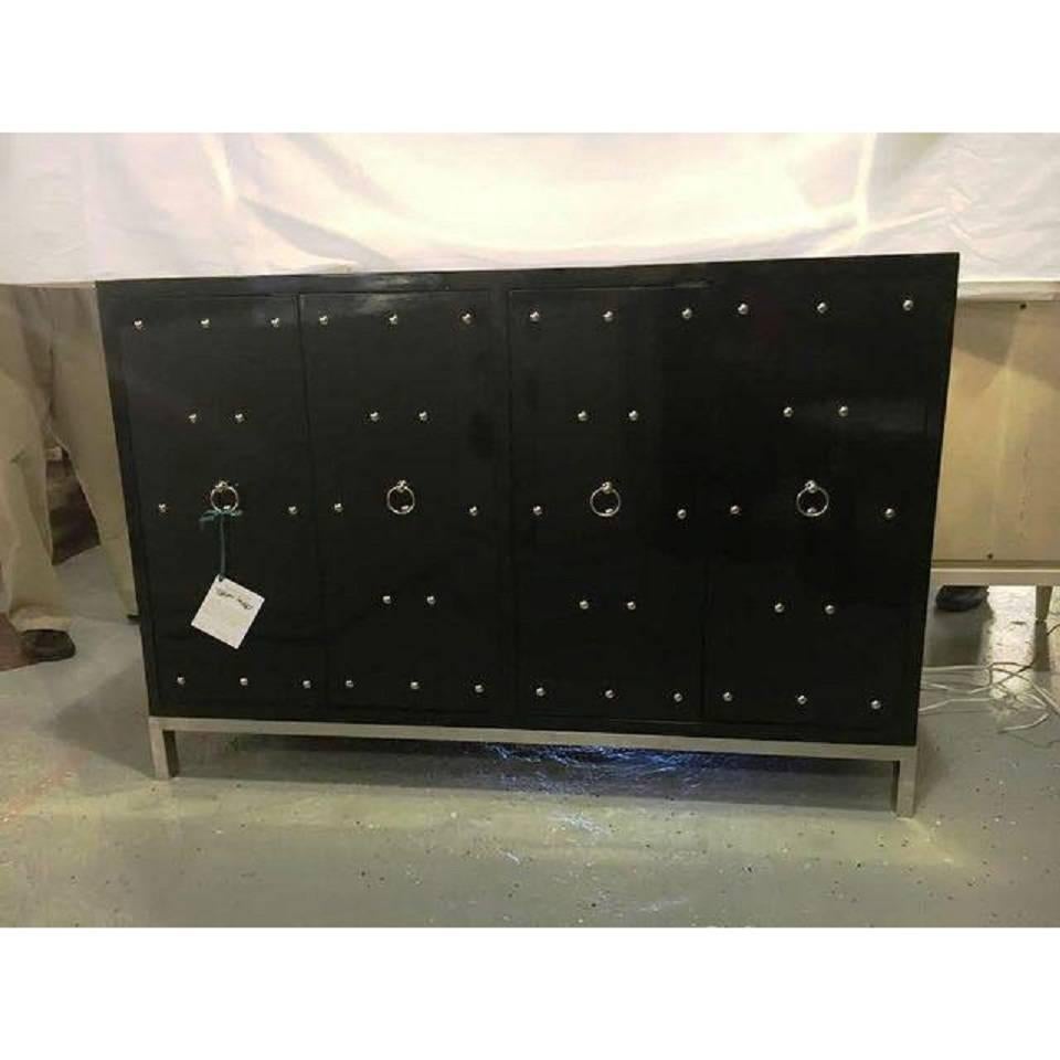 Tommi Parzinger style black studded and mirrored cabinet. A silver steel base supporting a four-door black lacquered and steel studded cabinet. The whole having a beveled mirror top and silver colored pulls.