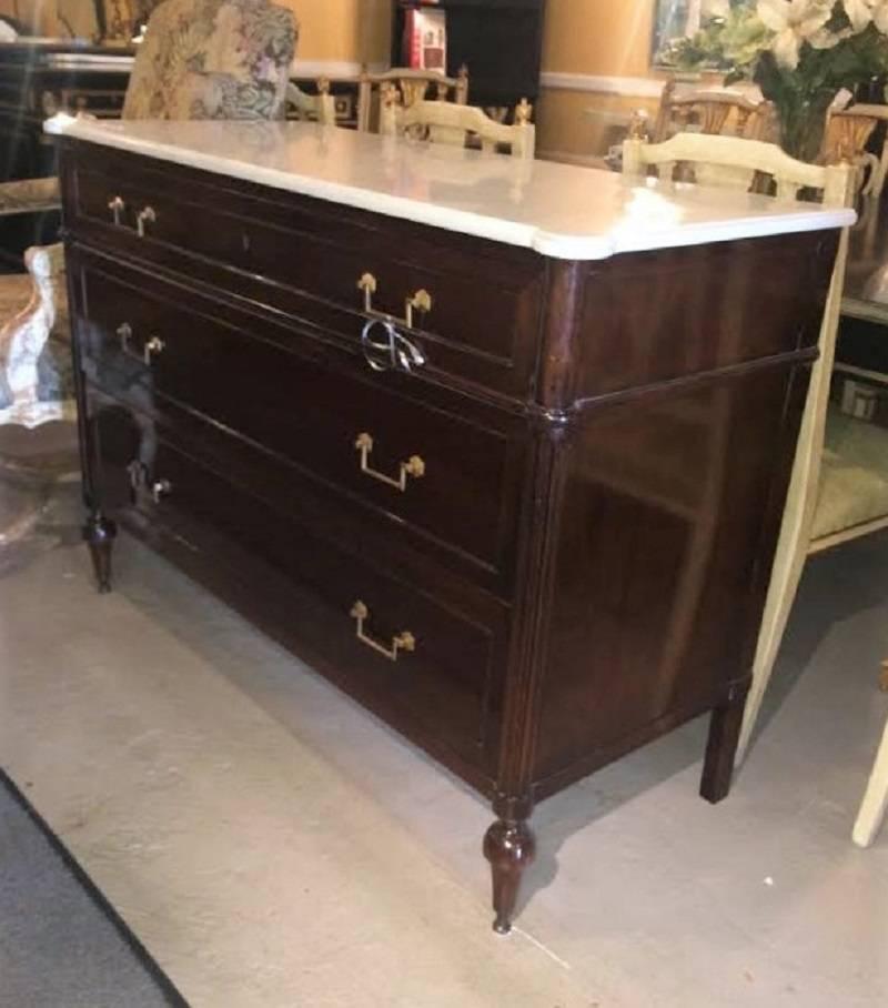 A mahogany Louis XVI style commode, beautiful marble-top with three drawers, raised on tapering legs ending in toupie feet stamped Maison Jansen. A nice grain mahogany with simple and sleek lines having three drawers all with bronze pulls. The case