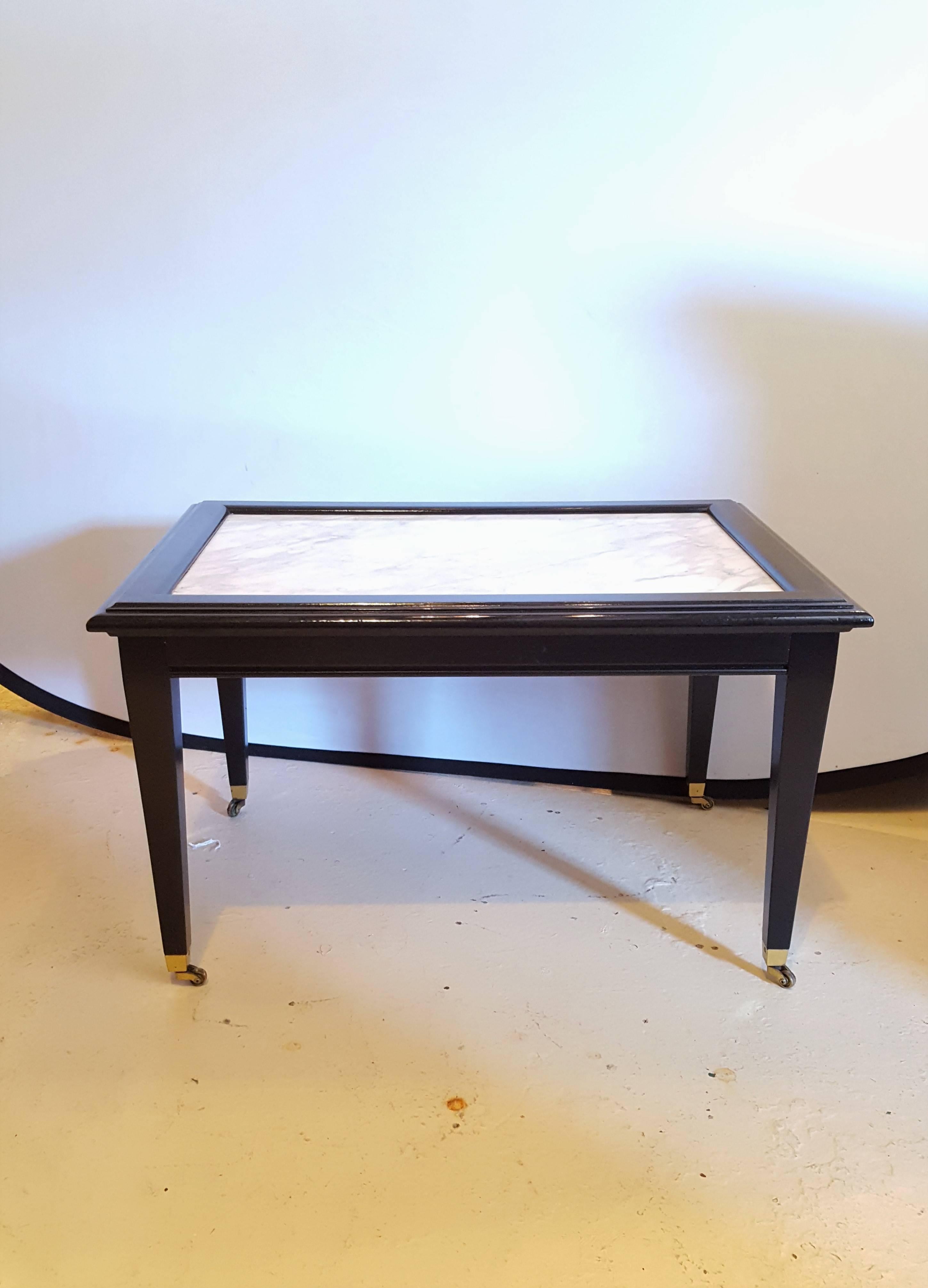 A small ebonized marble top coffee table. Bronze-mounted, in the Maison Jansen manner. This coffee table is on wheels, which makes it easy to move, a perfect accent piece for any room.