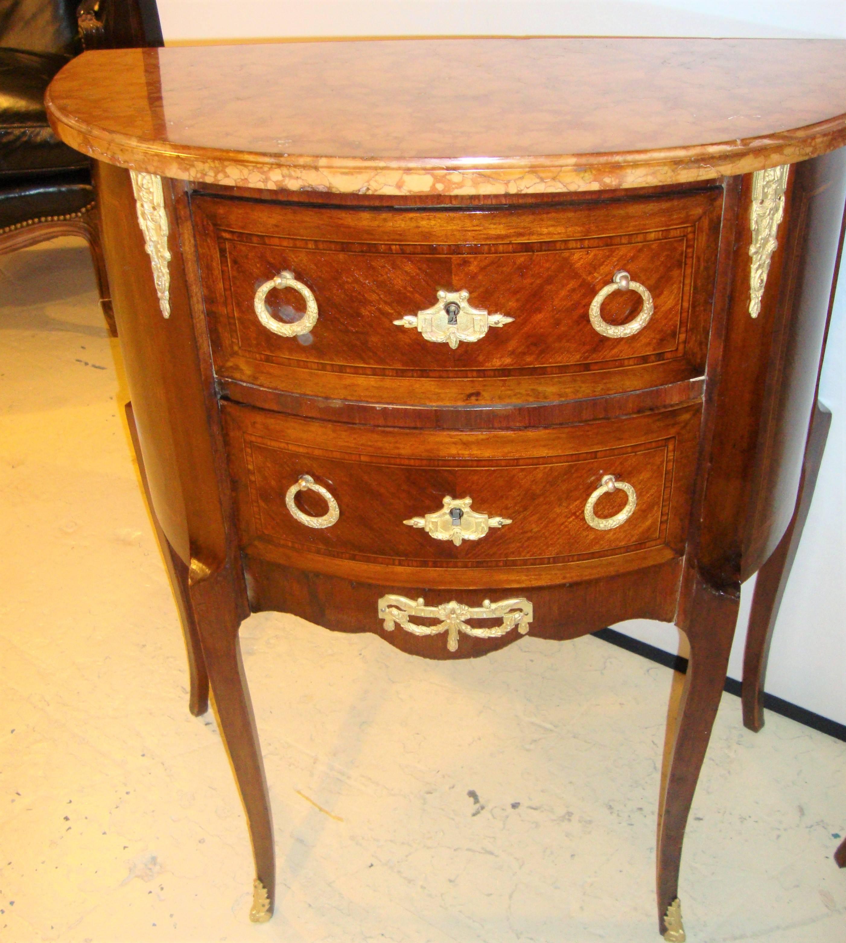 Pair of French demilune diminutive commodes or nightstands. Each recently French polished and cleaned. Finely inlaid supporting marble tops. Both stamped France.