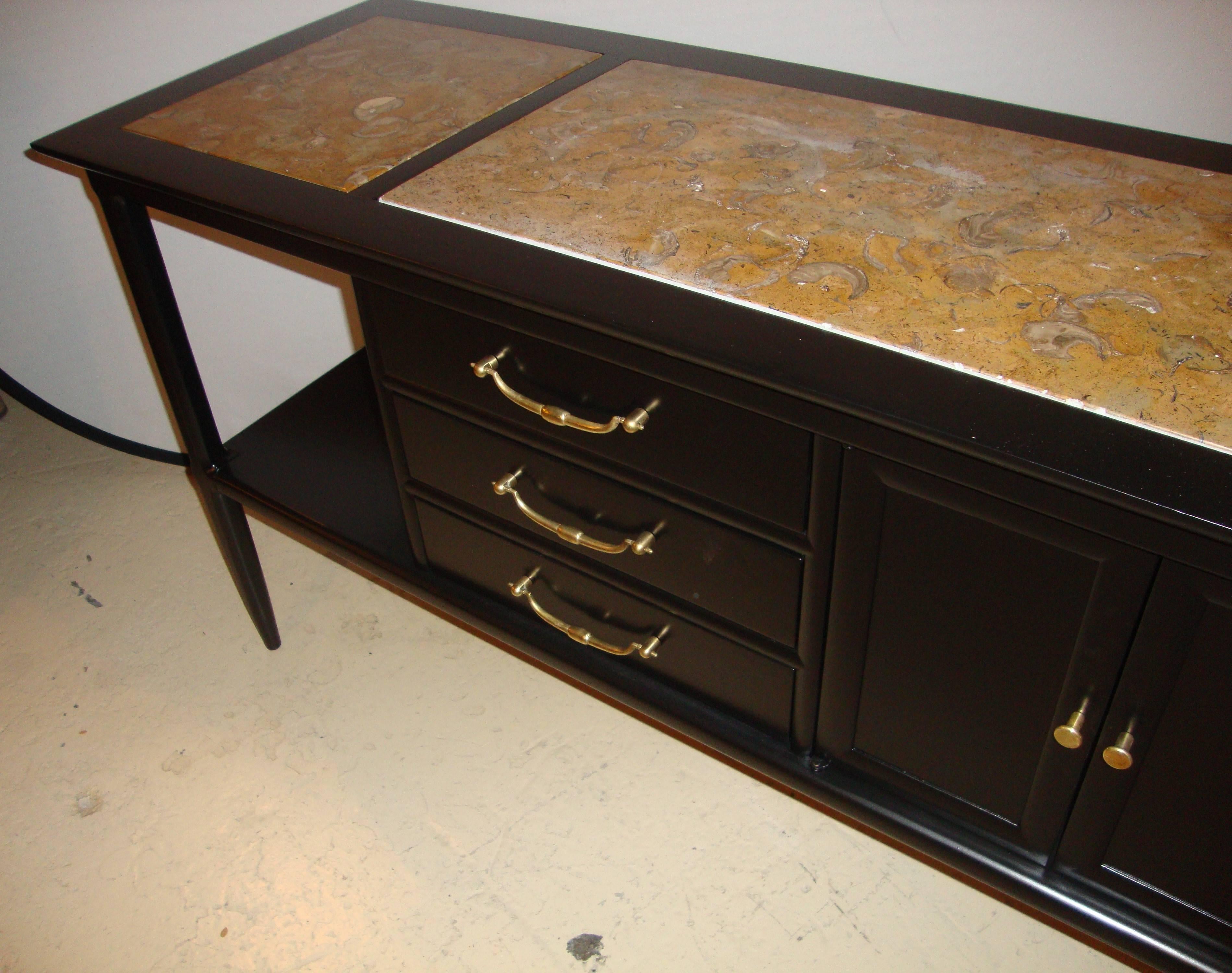 Pair of Tomlinson stamped marble-top ebonized credenzas or console tables. Each of custom quality having cultured marble insert tops supported by an ebony case having three center drawers flanked by side doors and open compartment areas. This pair