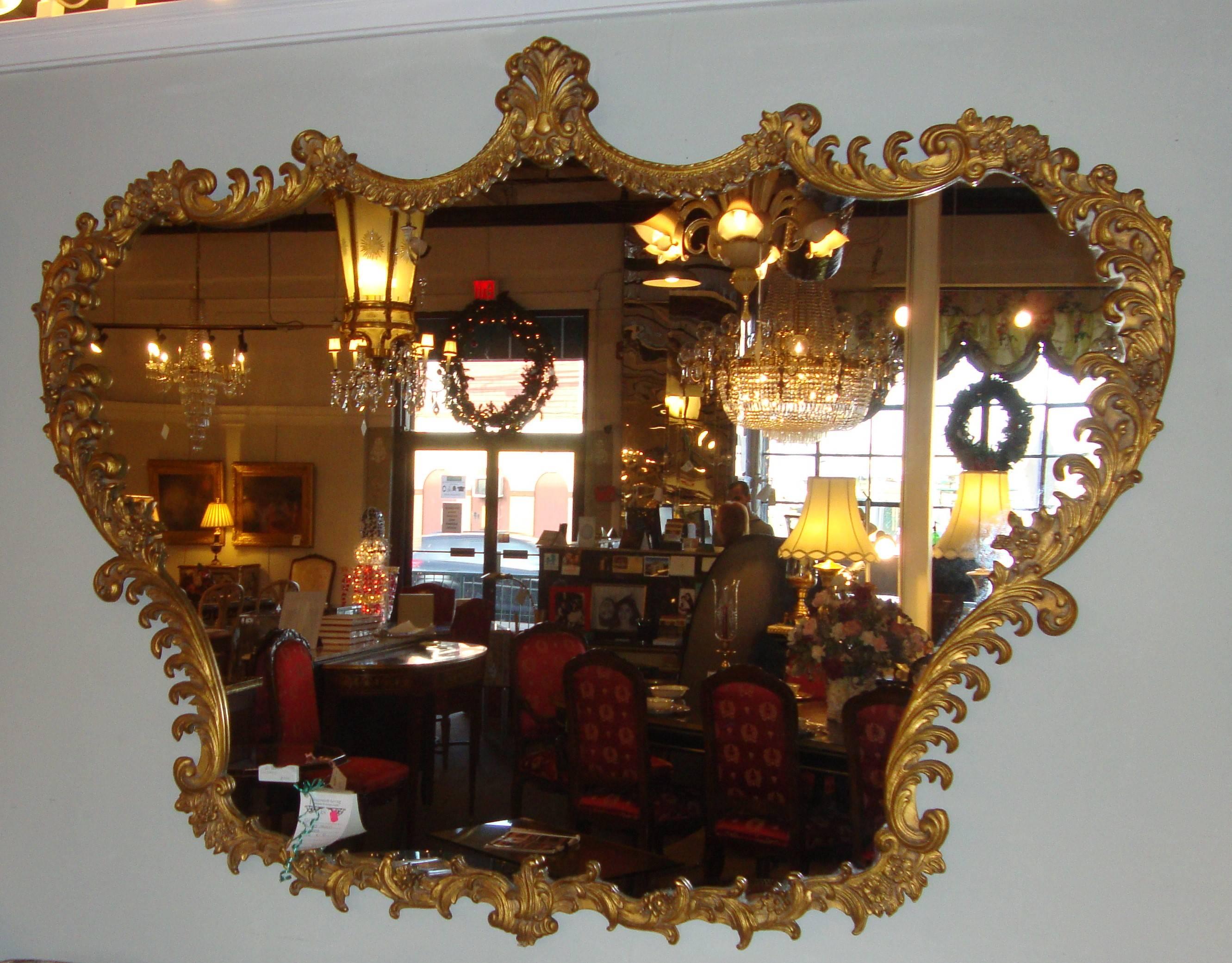 Giltwood Baroque carved horizontal mirror. Finely carved frame bordering an enormous central mirror. The border of gilt gesso and wood carved swags, leafs and vines.