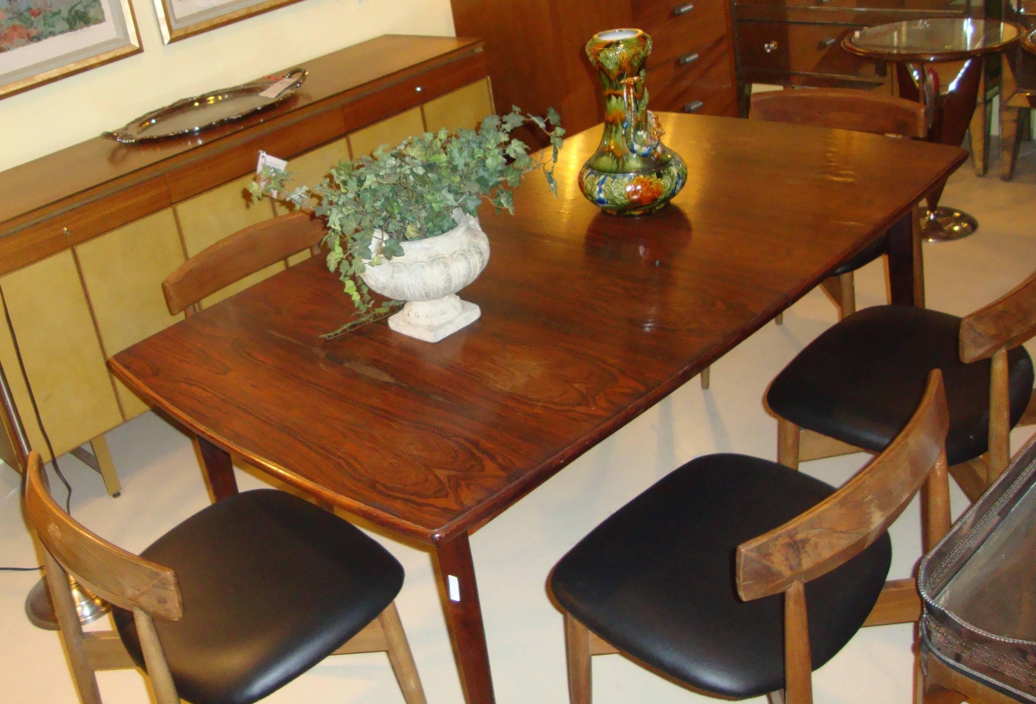 A Mid-Century Modern stamped dining table in rosewood. This solid wooden dining table is stamped on the underside Made in Norway. The rosewood top standing on four tapering legs. The top itself without leaves is in need of refinishing. This table is