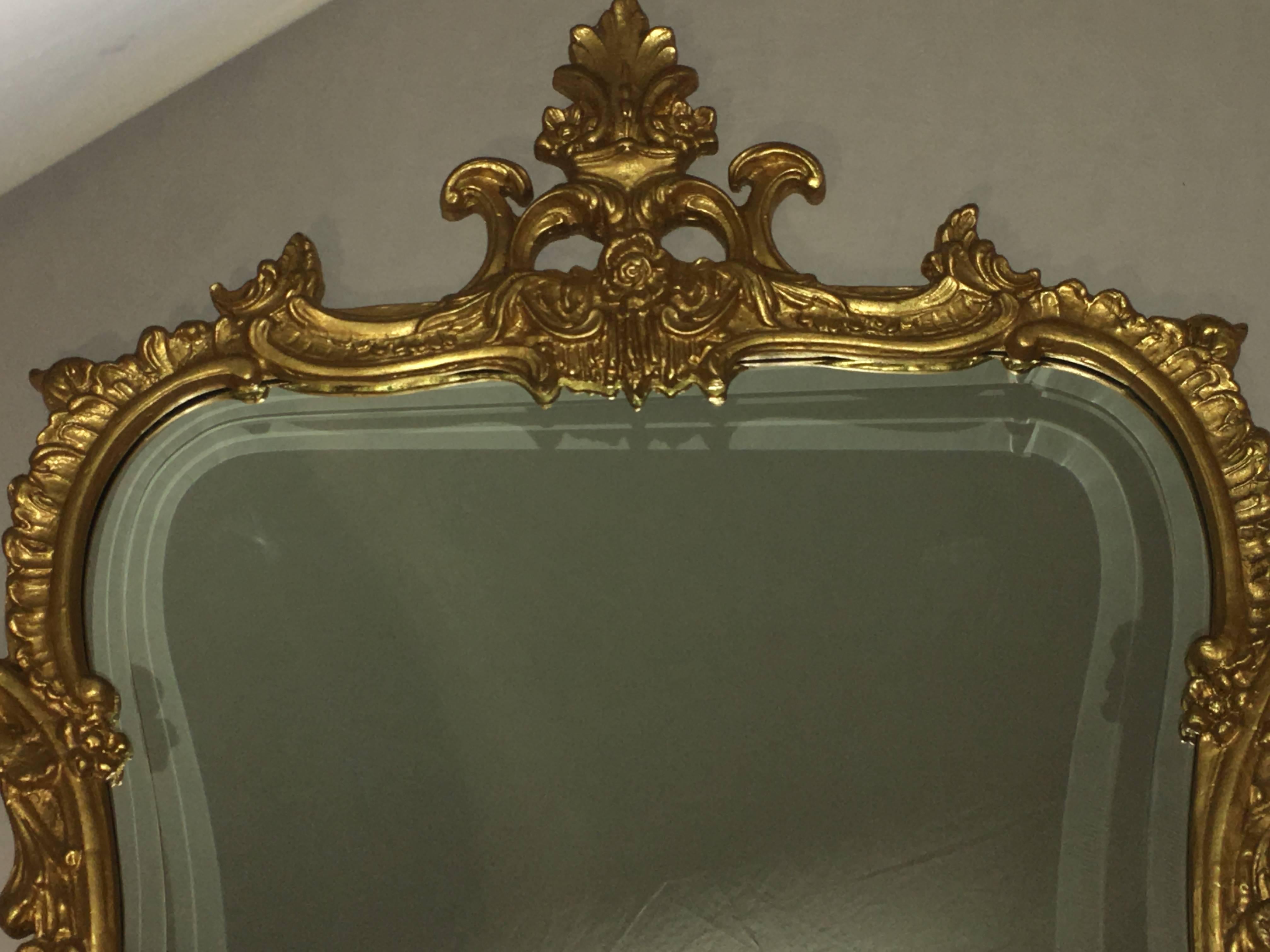 Pair of console or Wall Mirrors. Chippendale fashioned. Each center beveled frame mirror having a giltwood decorated frame. The frame itself has pierced carvings of roses, scrolls and leaf design. Each signed by Friedman Bros and custom quality.