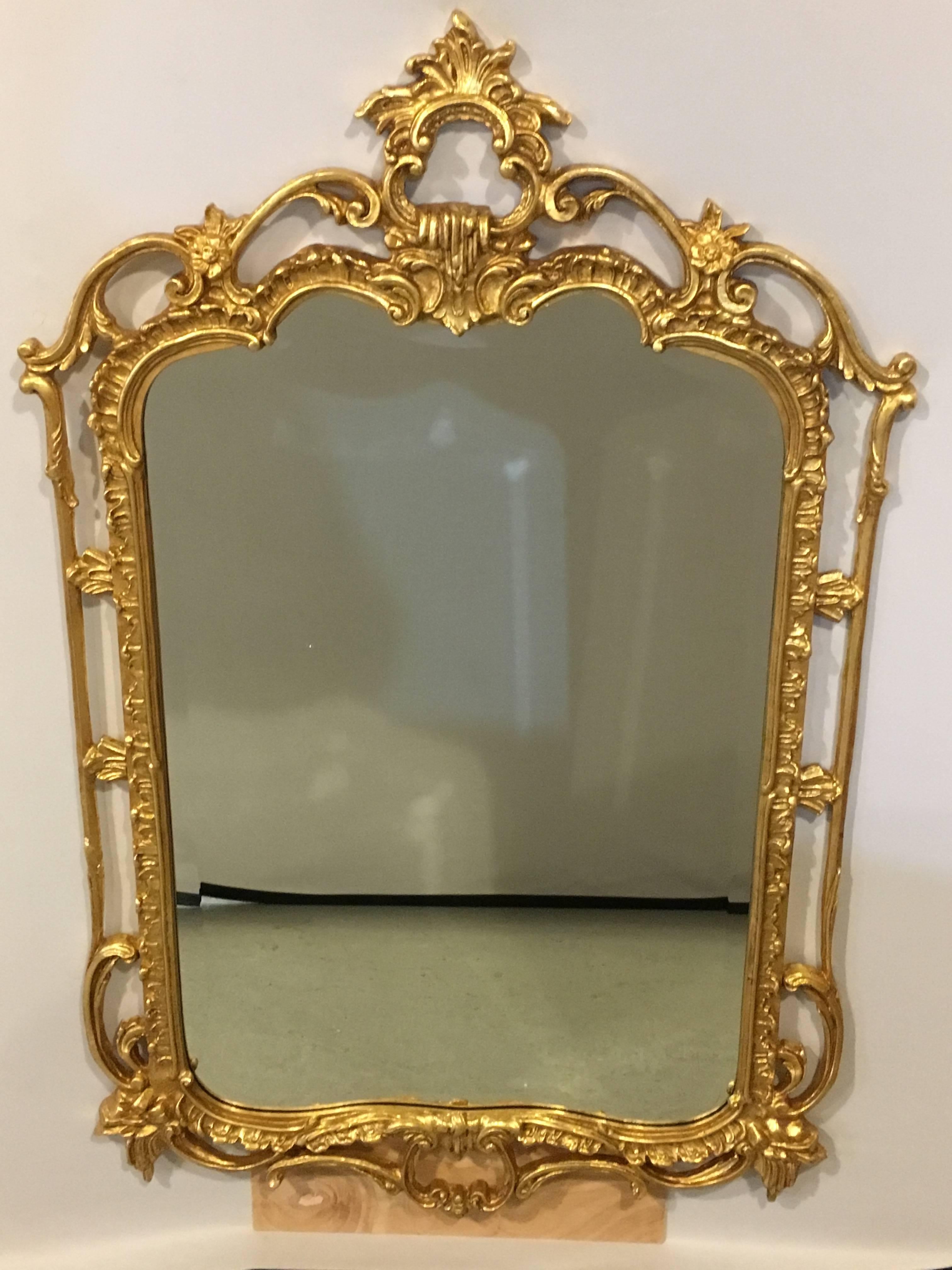 A pair of giltwood pierced carved wall console mirrors. A pair of custom quality giltwood mirrors. Each having a beveled center mirror panel framed in a Chippendale style carved frame. Custom-made by Friedman Bros.