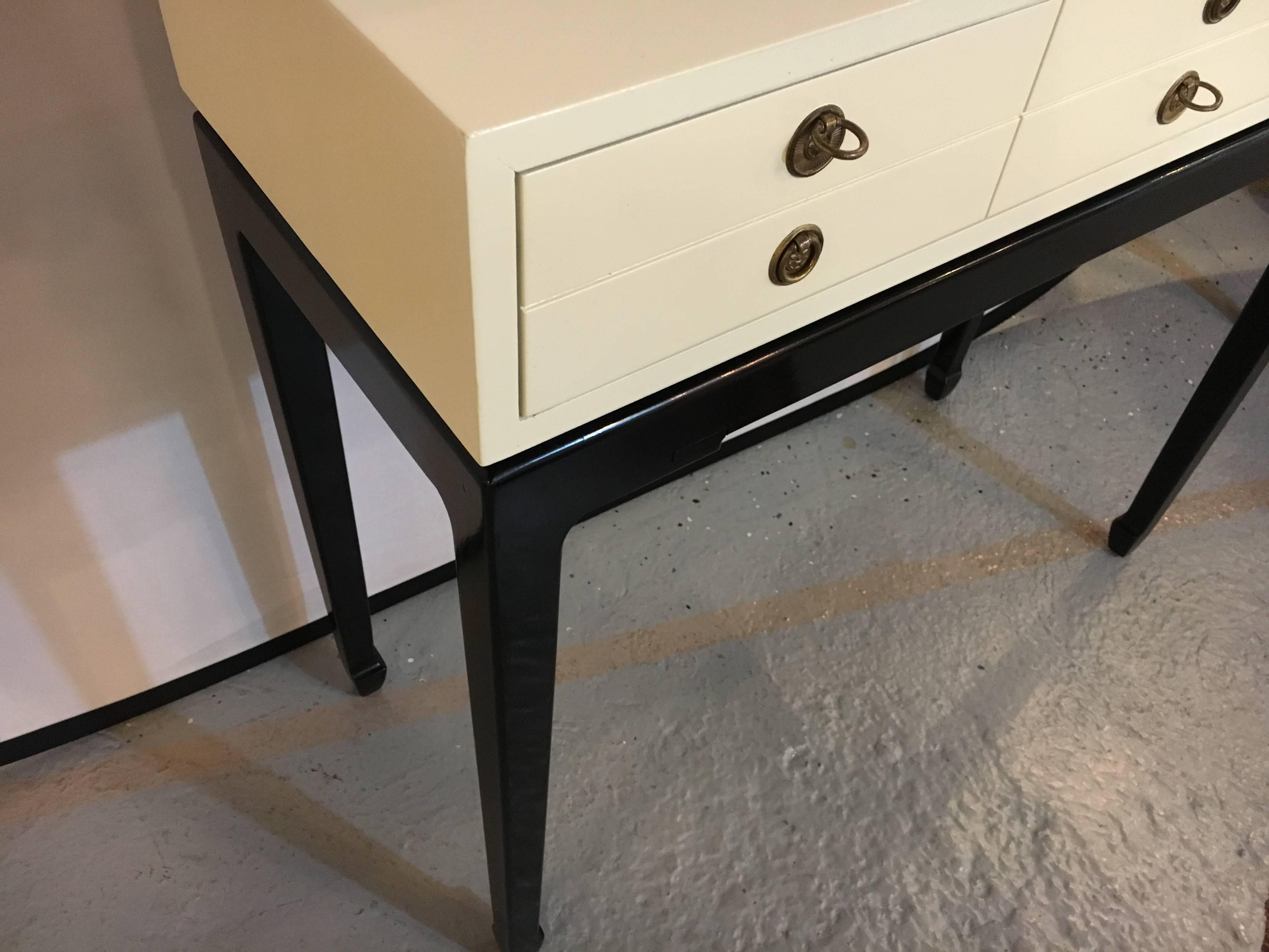 Tommi Parzinger style console table. The recently refinished table having an ebonized base with a one drawer custom quality case. The drawer with six brass pulls. Very sleek and stylish. Solid wood construction.