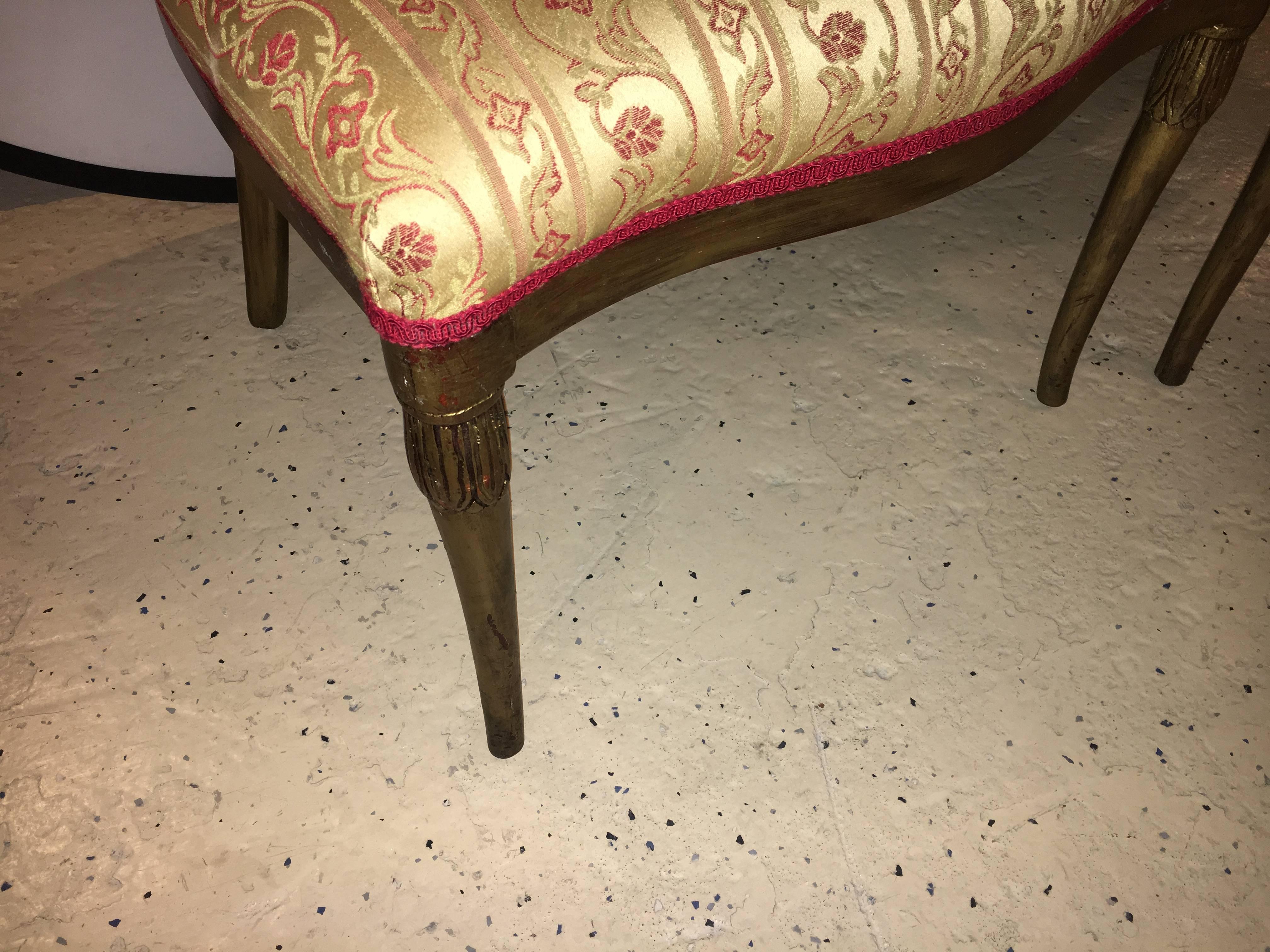 Pair of flame back fireside or armchairs. Each having a flame Art Deco style backrest leading to a padded seat. The entire chair having a gilt gold distressed wood frame.