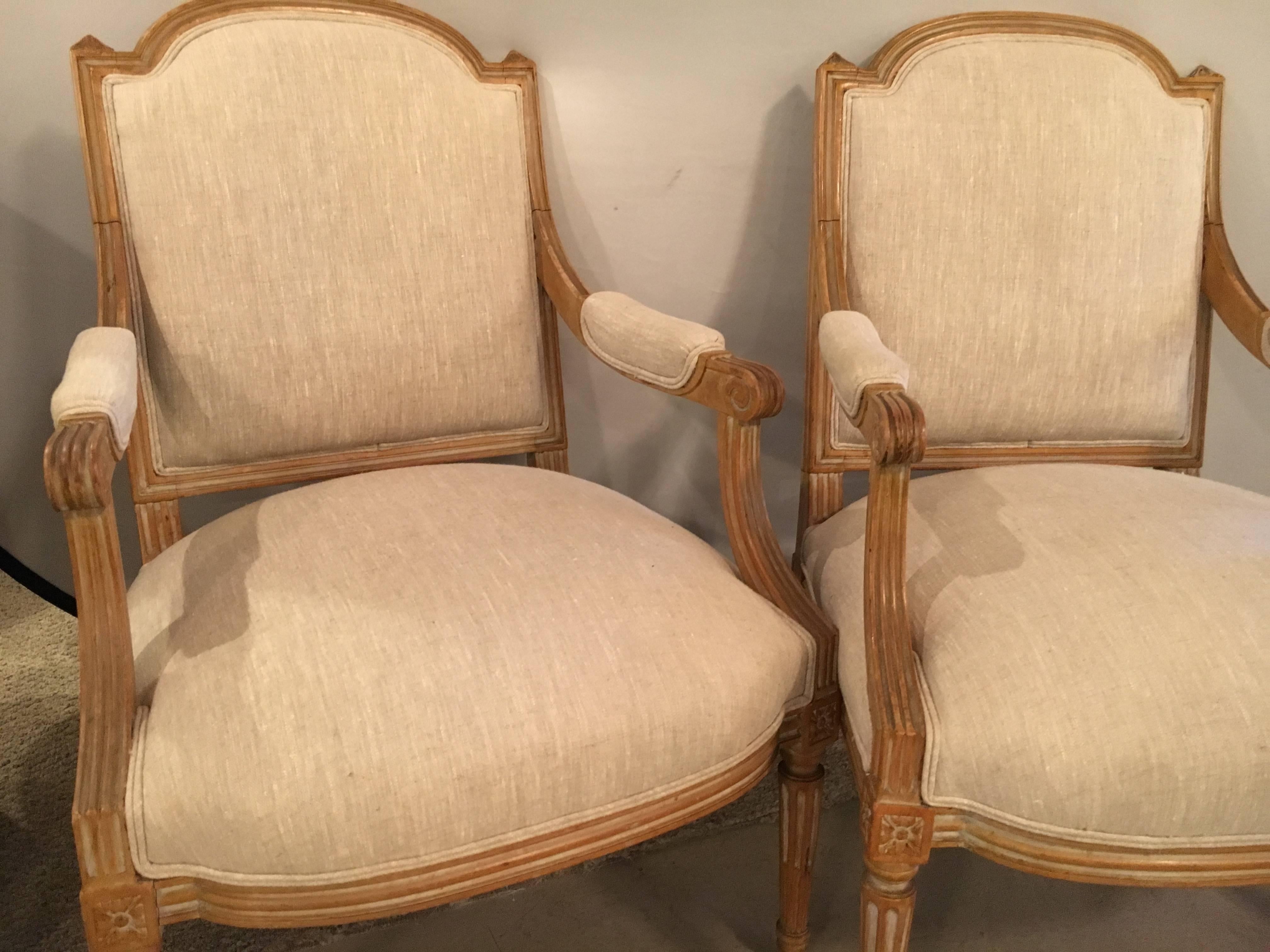 A pair of Maison Jansen Louis XVI style Fauteuils or armchairs. A finely detailed pair of pickled finish open armchairs in the Louis XVI fashion. Each having new fabric. The wide squarish backrests supported by an overstuffed very comfortable seat
