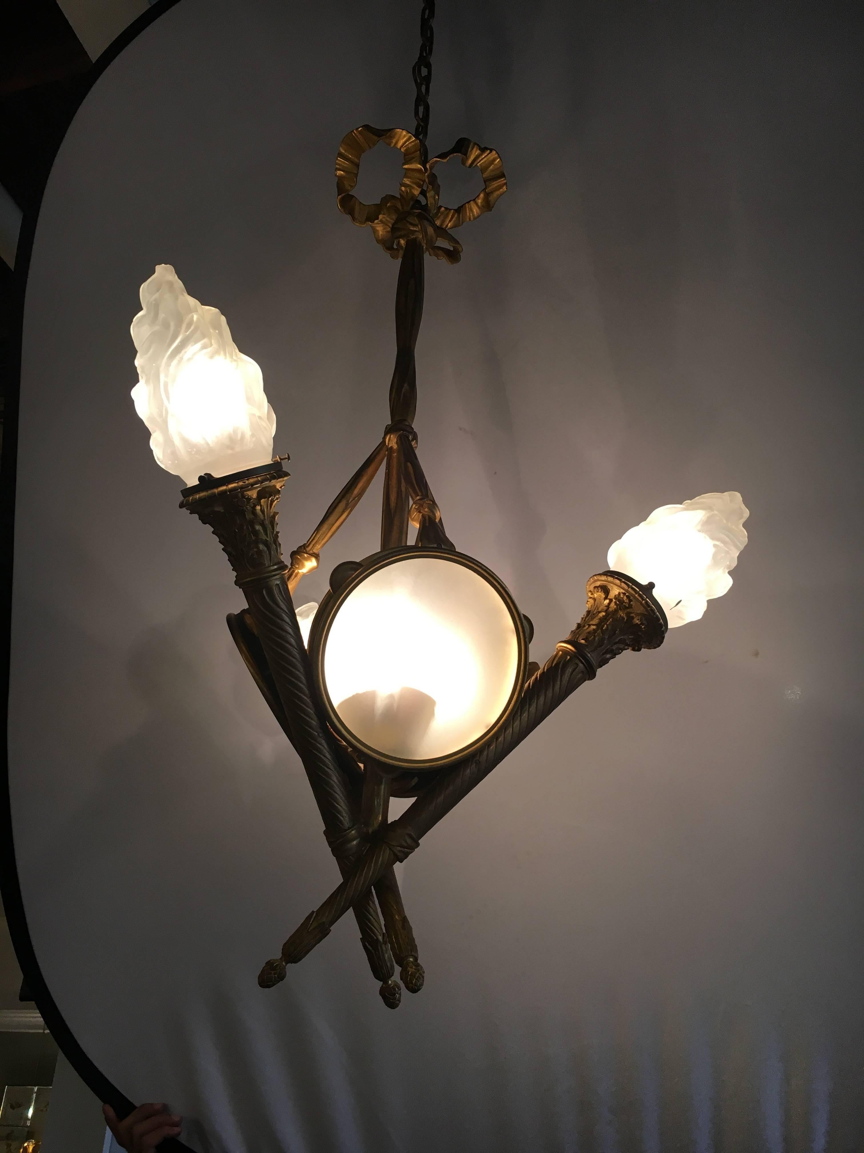 Louis XVI style chandelier. The corona with swags and flaming finial with three interior lights over three cobalt blu drums having frosted shande and three Laligue style globes having three additional lights. The chain approximately 52 inches long