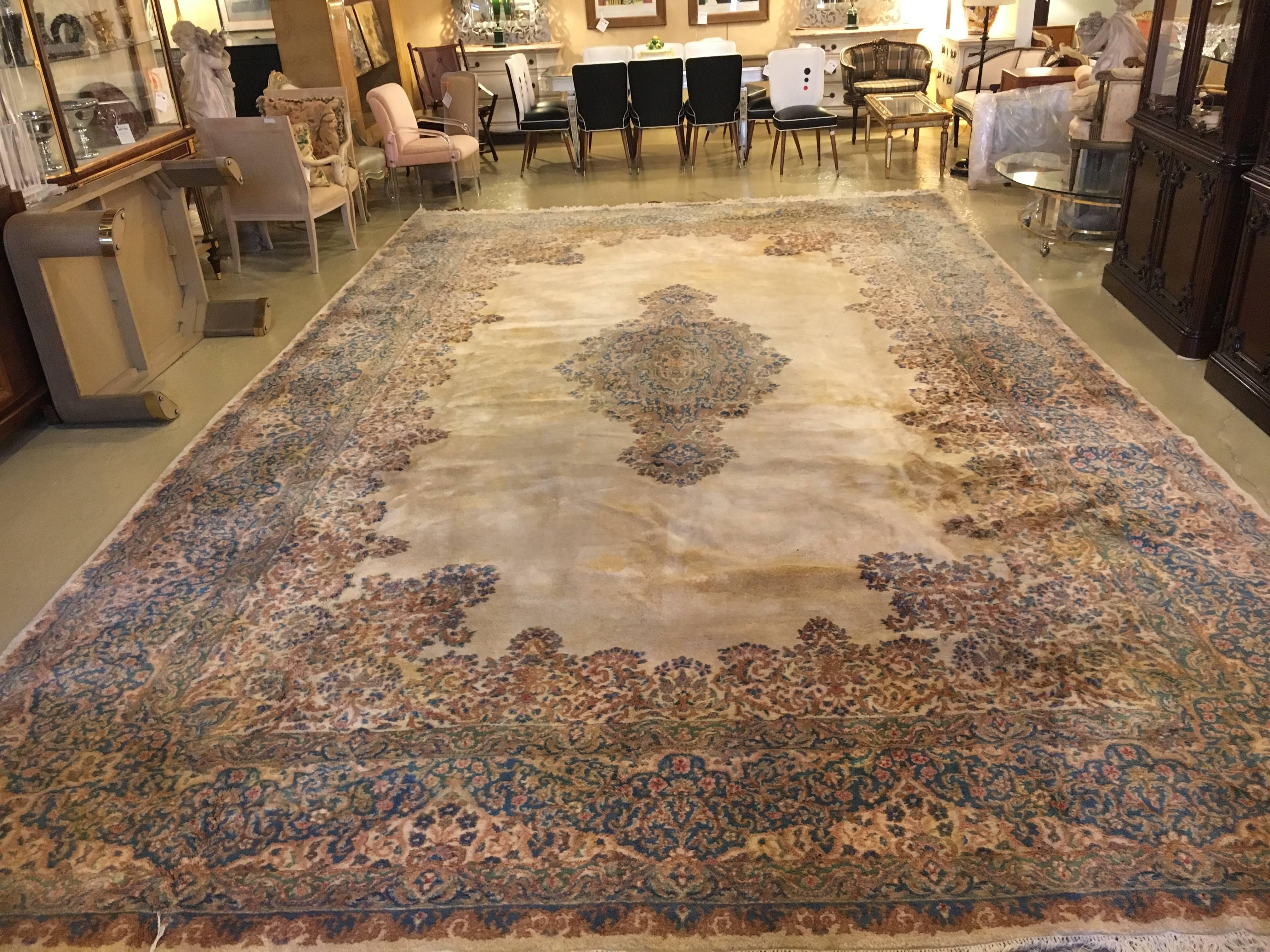 This open field Kirman carpet has vibrant and colorful borders as well as a vibrant and colorful center medallion. The rich thick border with celeste blu and rust tones having brown, orange and different beige tones. The center medallion matching