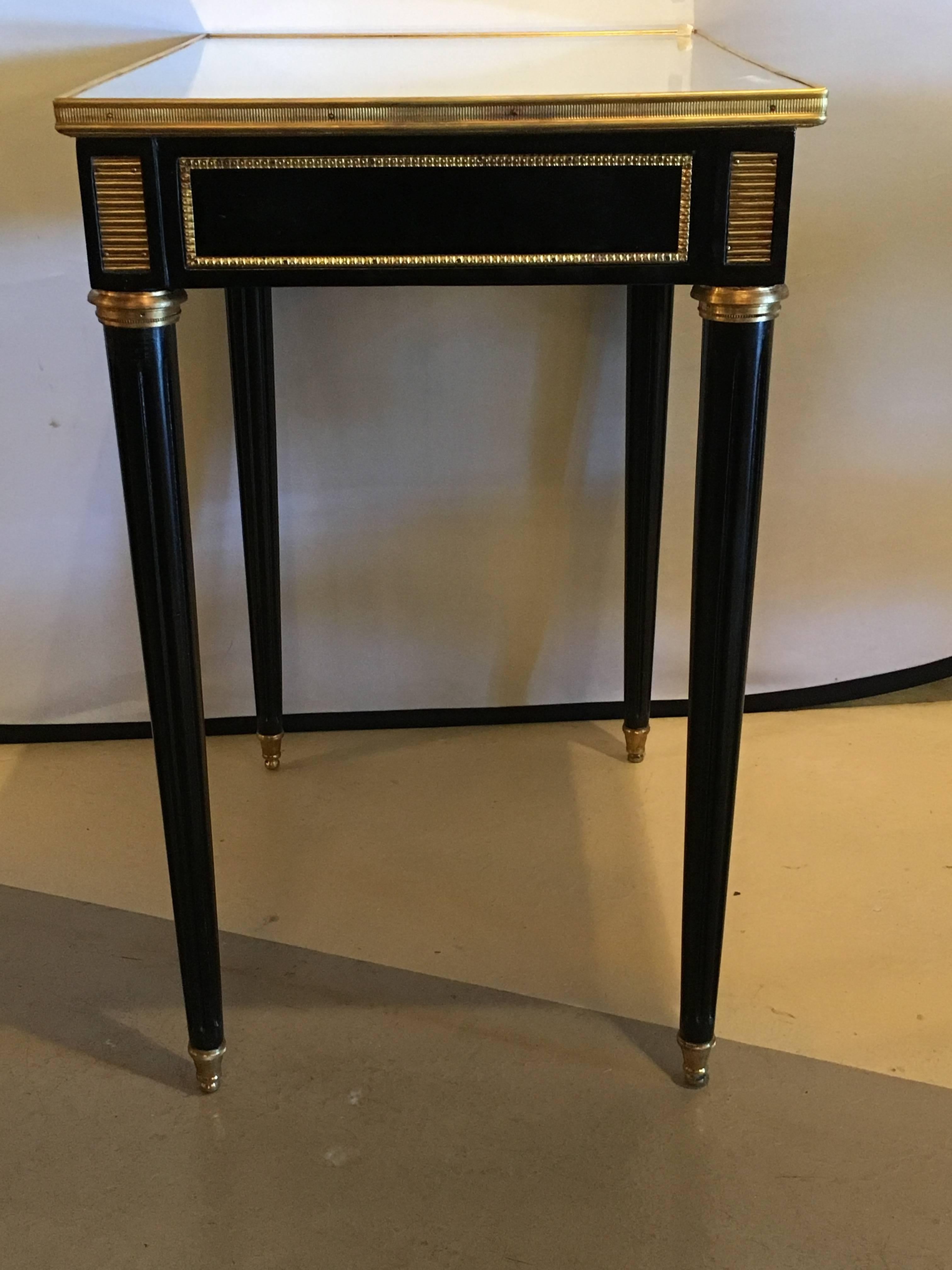 Pair of Jansen style ebonized mirror top end tables or stands. The Louis XVI style end or nightstands are finely ebonized having one drawer each. The mirrored bronze framed top leading to an apron which has been bronze framed and has cookie cutter
