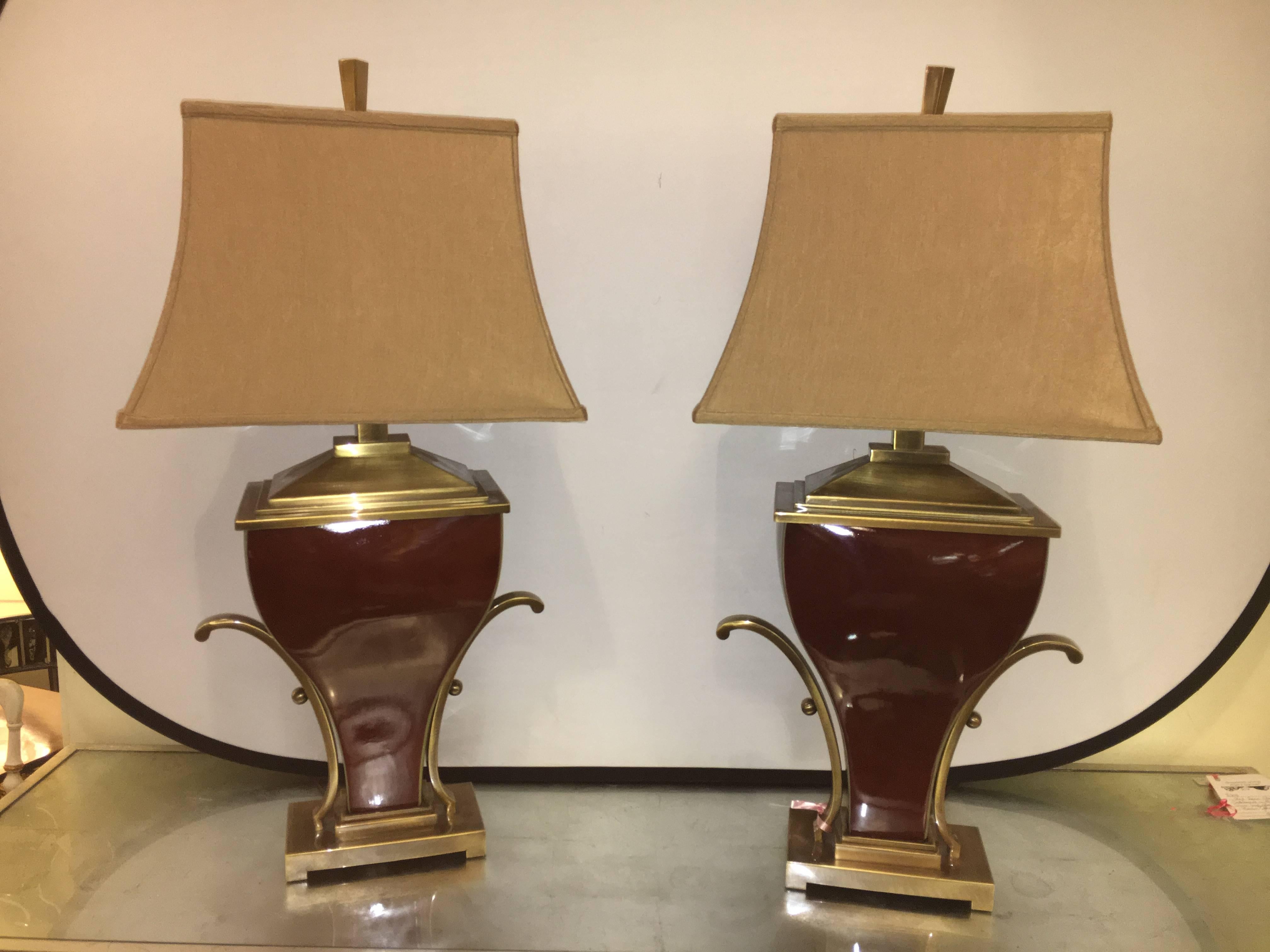 Pair of Art Deco style brass-mounted porcelain table lamps. An extremely decorative pair of urn form table lamps with brass mounts. Each lamp complete with brass finial and custom quality shades. The Burgundy Urn form centres having flowing arms