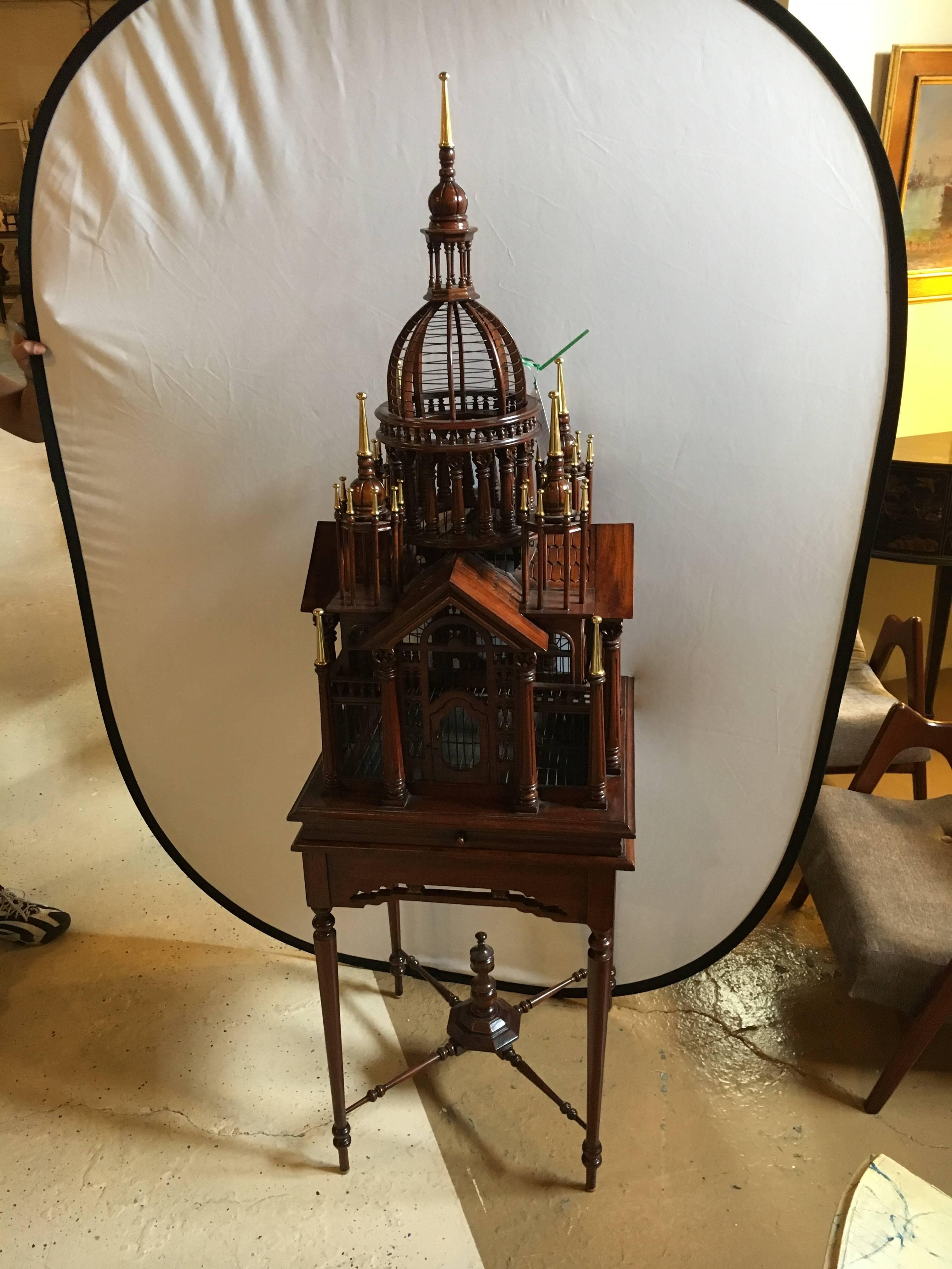A Victorian style bird cage on a stand. The 43 inch birdcage itself sitting on a 28 inch high table with a removable tray. Having small doors that open and close on each side this fine brass-mounted bird cage is highly decorative.
