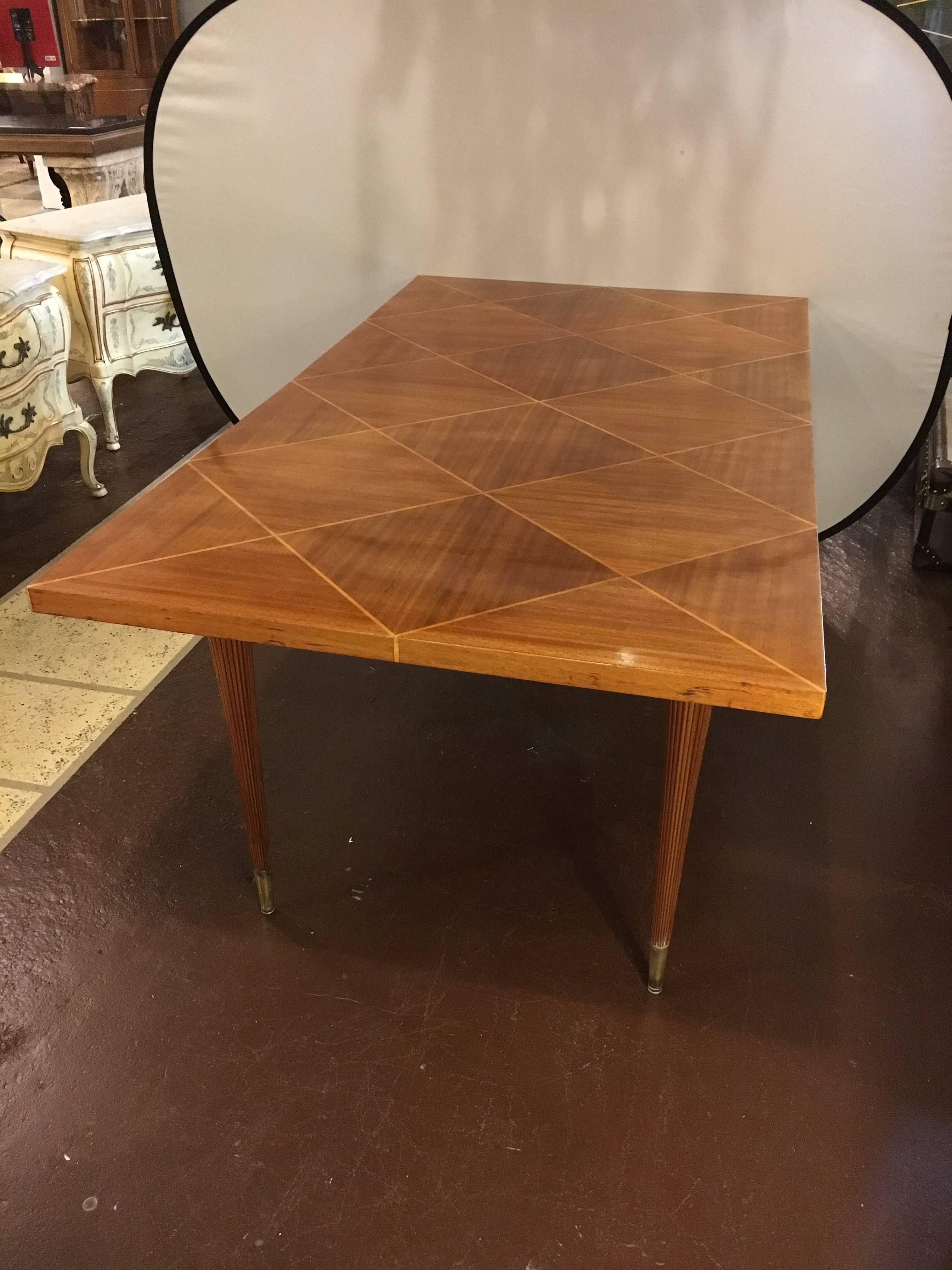Tommi Parzinger dining table with two leaves by Charak. Beautiful Tommi Parzinger for Charak extension dining table in flamed mahogany with a parquetry inlaid top and fluted brass capped legs. With two 17 inch leaves. Manufactured by Charak