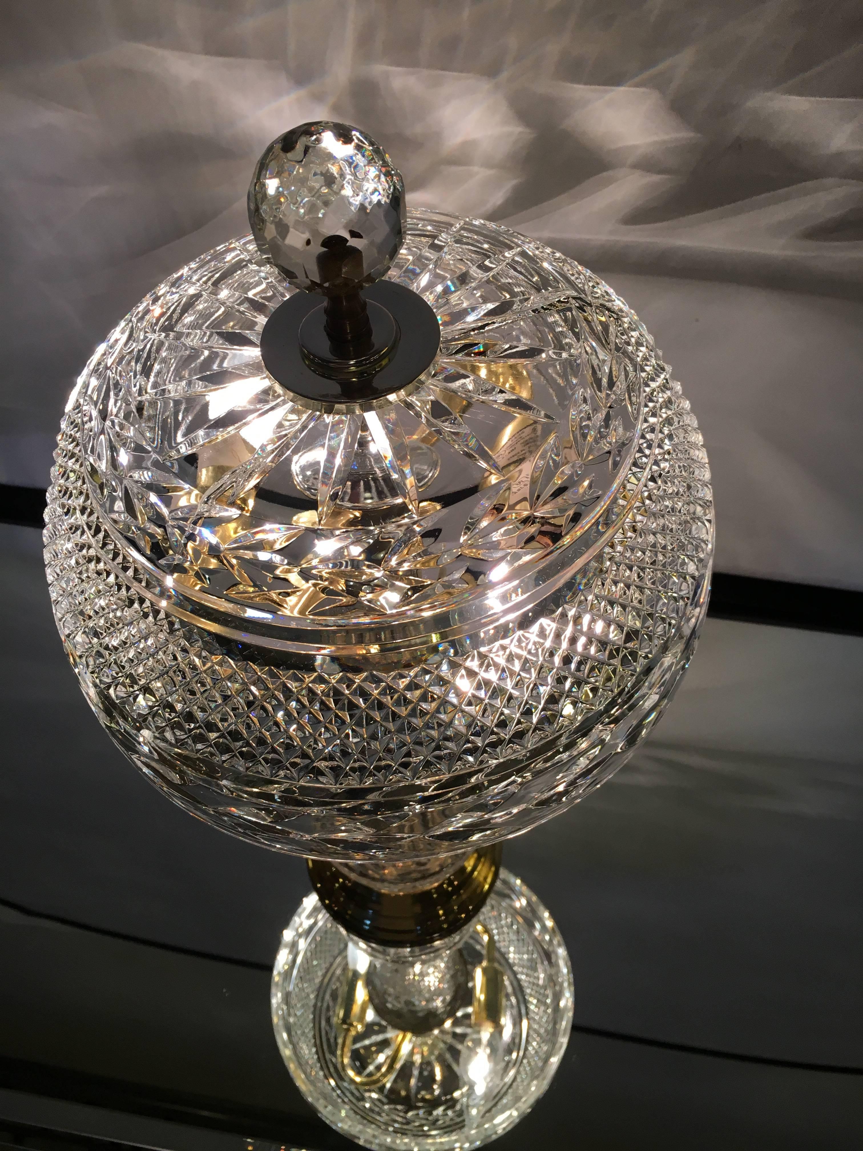 A crystal table lamp with crystal shade on a brass base. Having two lights.
