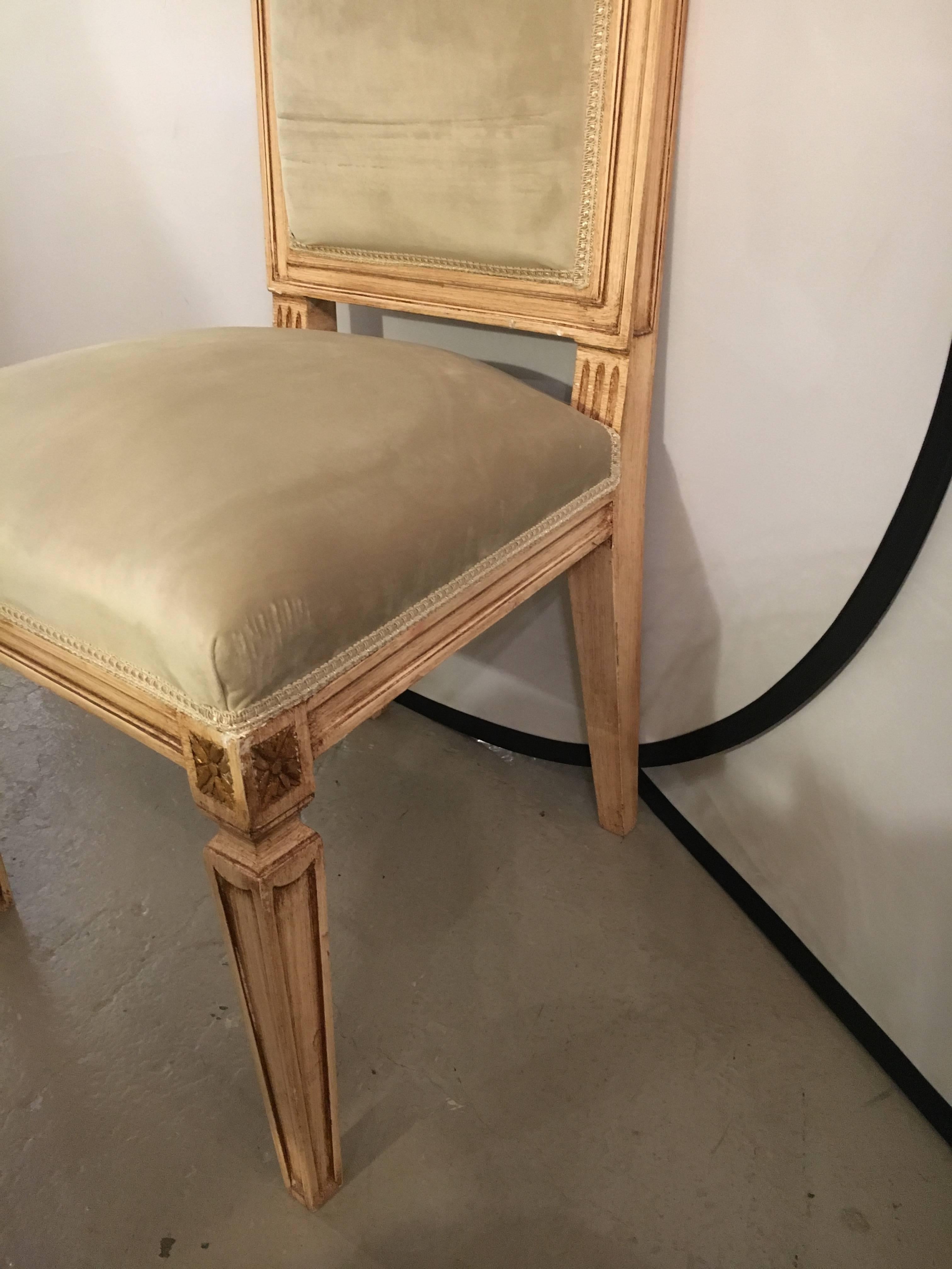 Set of 12 paint decorated Louis XVI Jansen style dining chairs. All in new suede upholstery. The fine tapering legs having incised lines. The square backs and seat design made popular by this iconic designer. All of parcel-gilt and paint decorated.