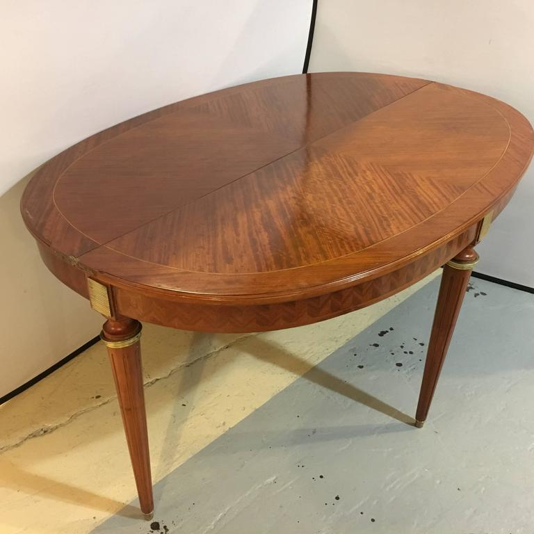 A Maison Jansen demilune console table converts into a dining table. This is an absolute must have. This fine parquetry inlaid demilune console converts, with a full apron of parquetry inlays, into an oval dining room table. The intricate rosewood