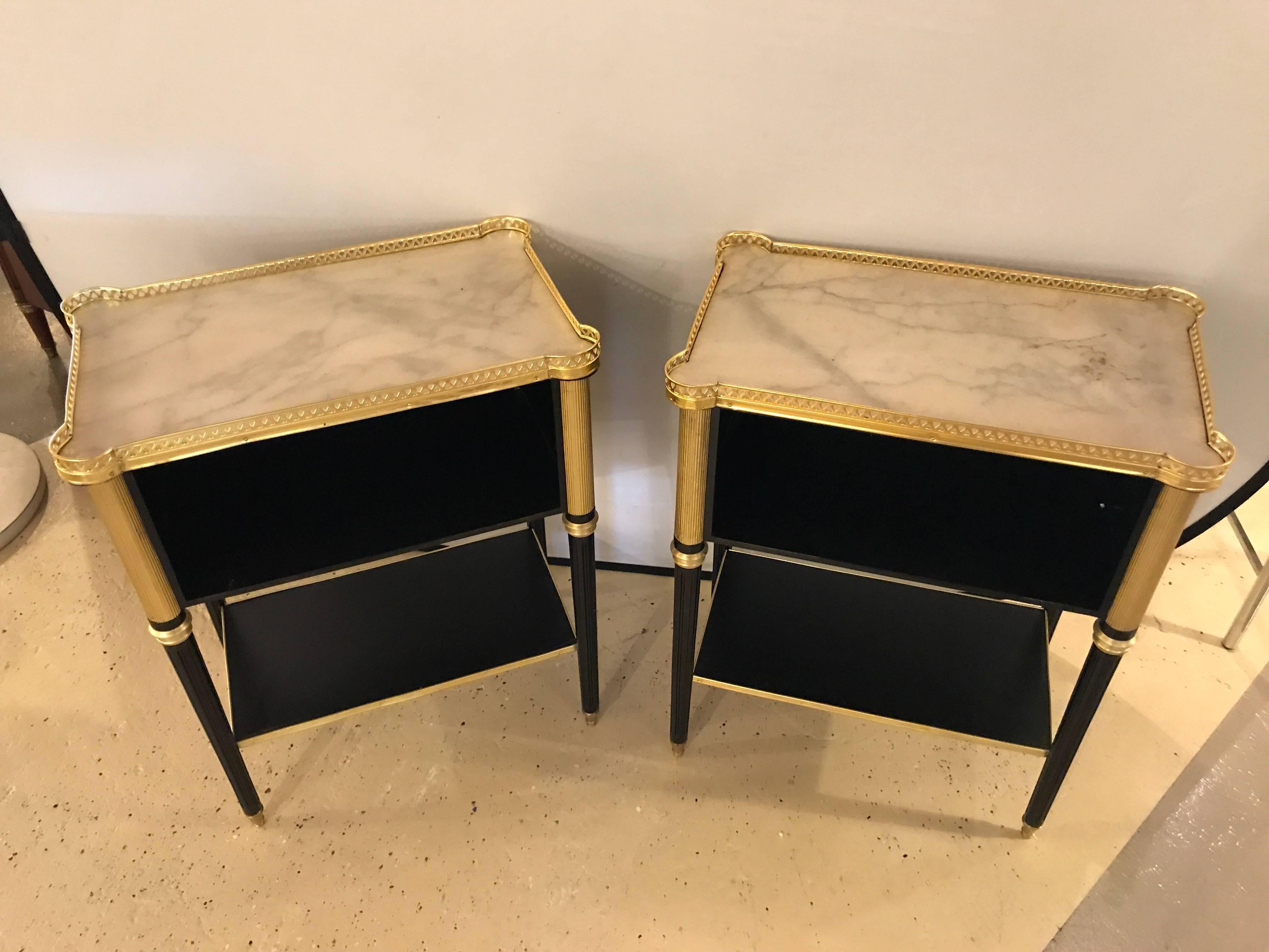 A fine pair of Jansen style marble-top end tables. This fine pair of Louis XVI style end tables or bedside stands depict the Jansen style and Hollywood Regency era flawlessly. The heavy bronze-mounted tapering legs have a bronze framed lower shelf