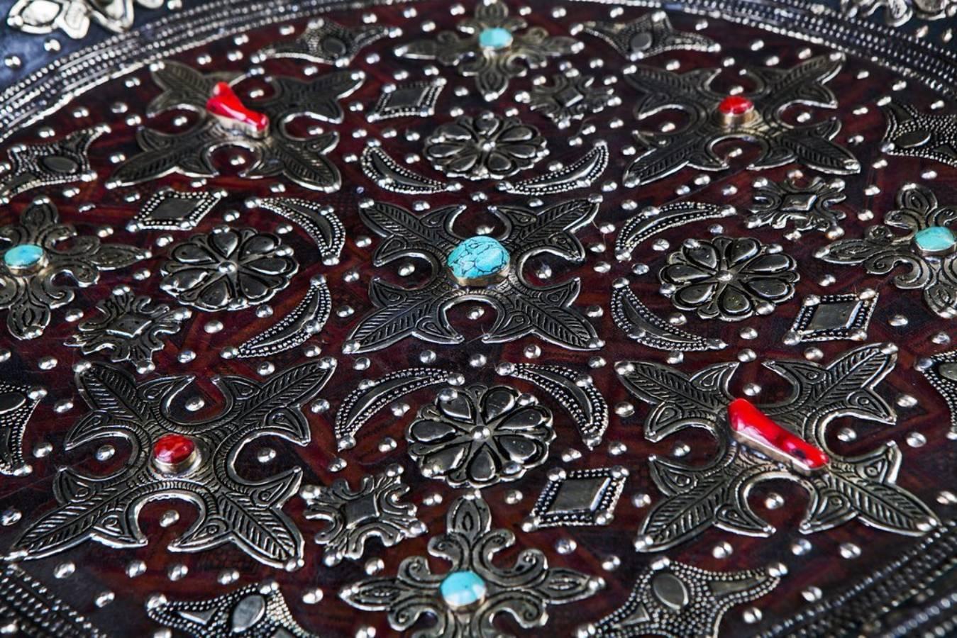 This wall decorative ancient style plate features intense, dazzling geometrical patterns on genuine leather, inlaid silver metal punctuated with painted natural stones and exotically designed arabesque motifs. Beautiful and compelling, this ancient