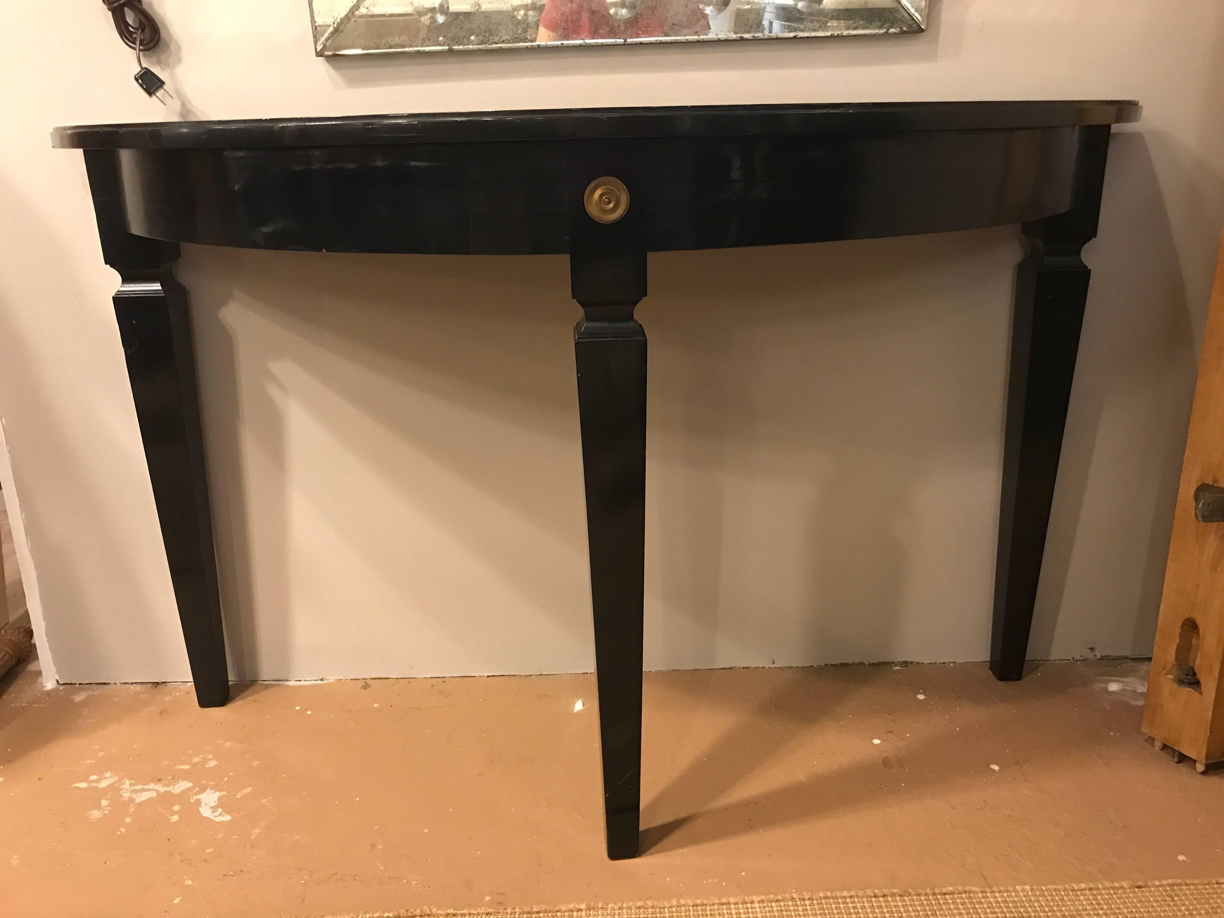 Églomiséd demilune console table by Maison Jansen. The ebonized base having long sleek tapering legs terminating in bronze circular decals. The base supporting a framed églomisé glass top of gold and silver design. This table showing the fine