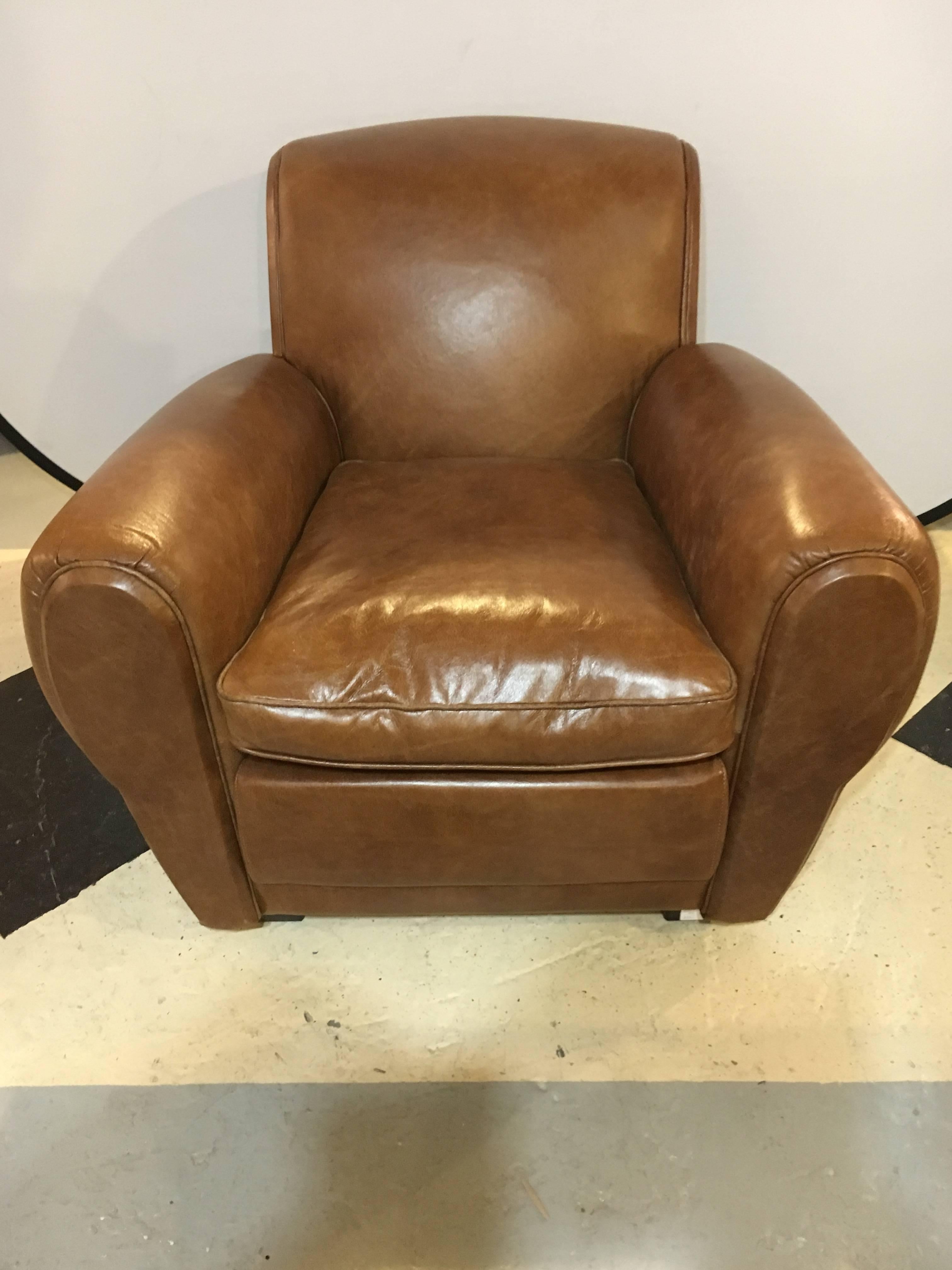 A pair of fine worn leather cabaret chairs. Each chair sitting on square bracket feet with burlap bottoms leading to a comfortable and easy lounge chair of worn brown leather with wide sitting areas. We have two pair of these chairs available. Price
